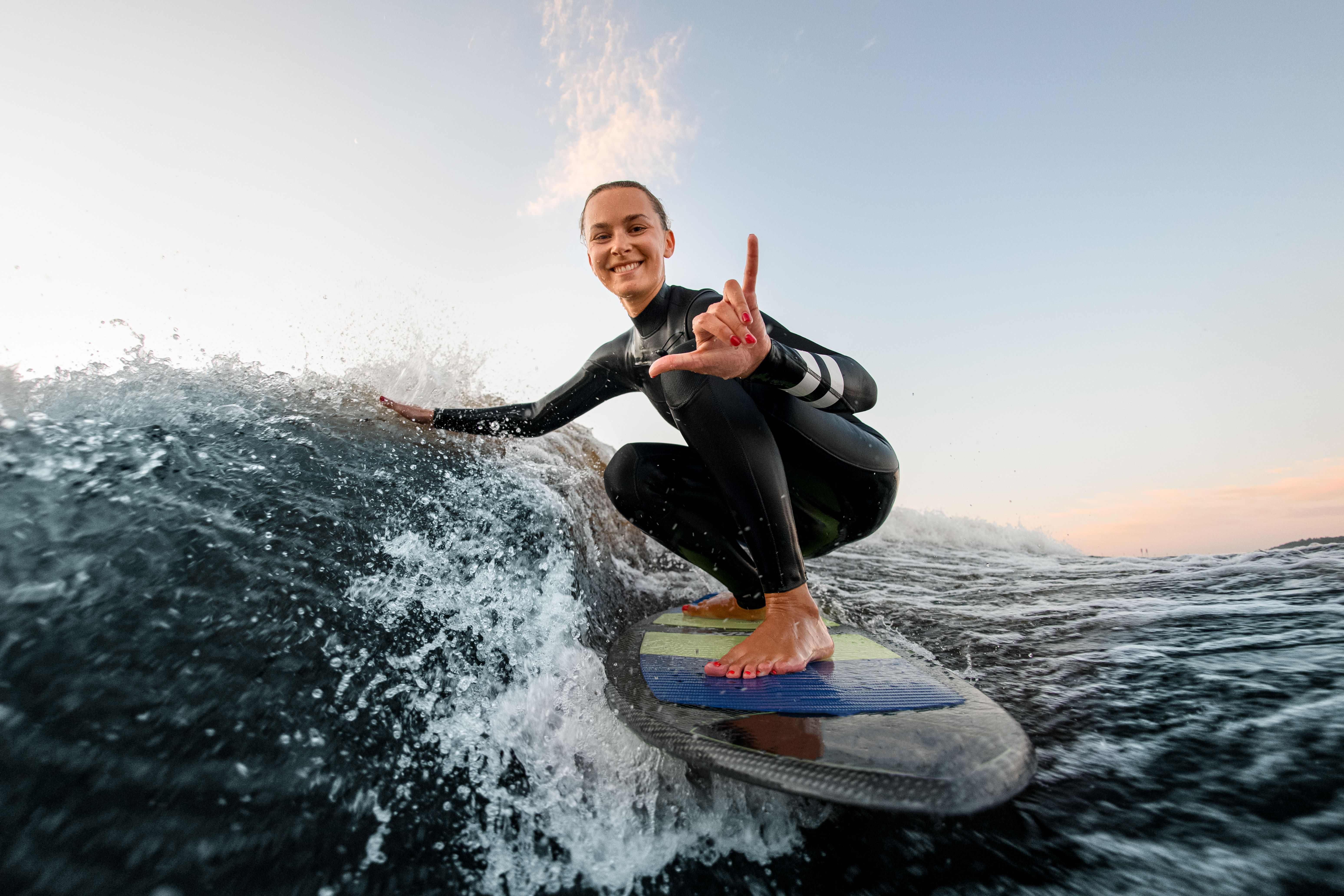 man instructor demonstrating how to stand up on surfboard to indian woman in surf class in Goa sea