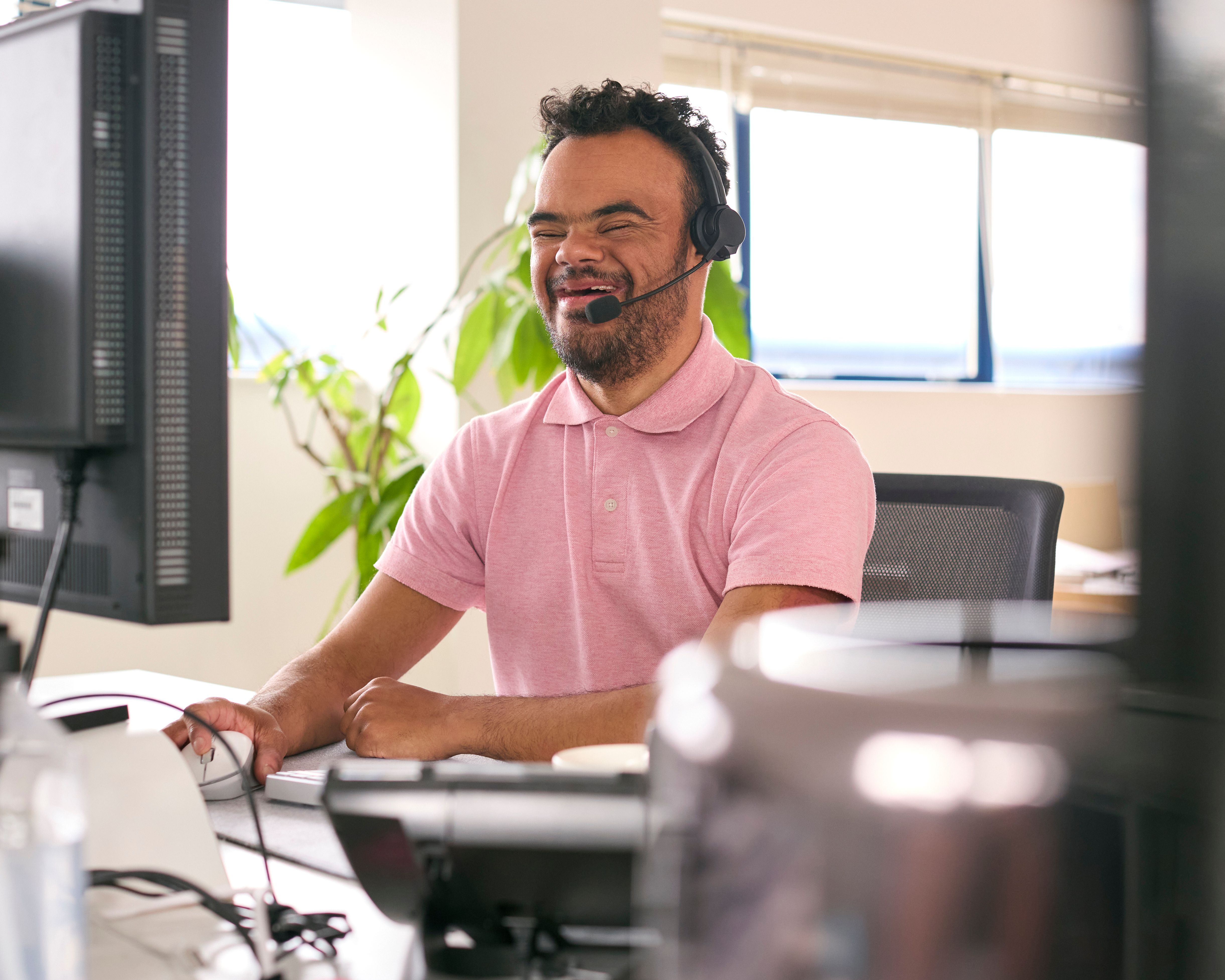 Man With Down Syndrome Wearing Headset Working In Office Call Centre