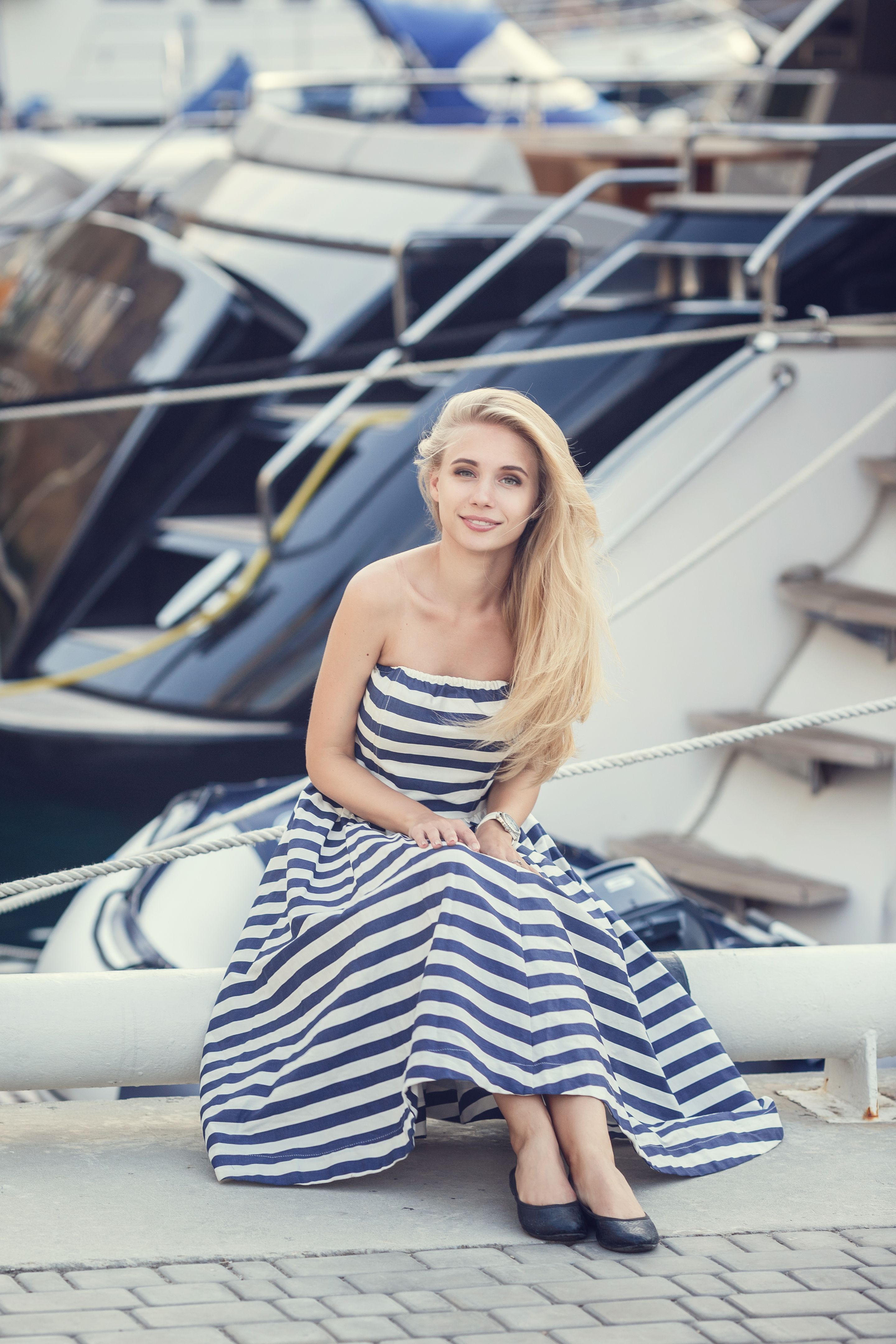 A beautiful little girl in a marine style against the backdrop of boats and yachts. Little Seaman