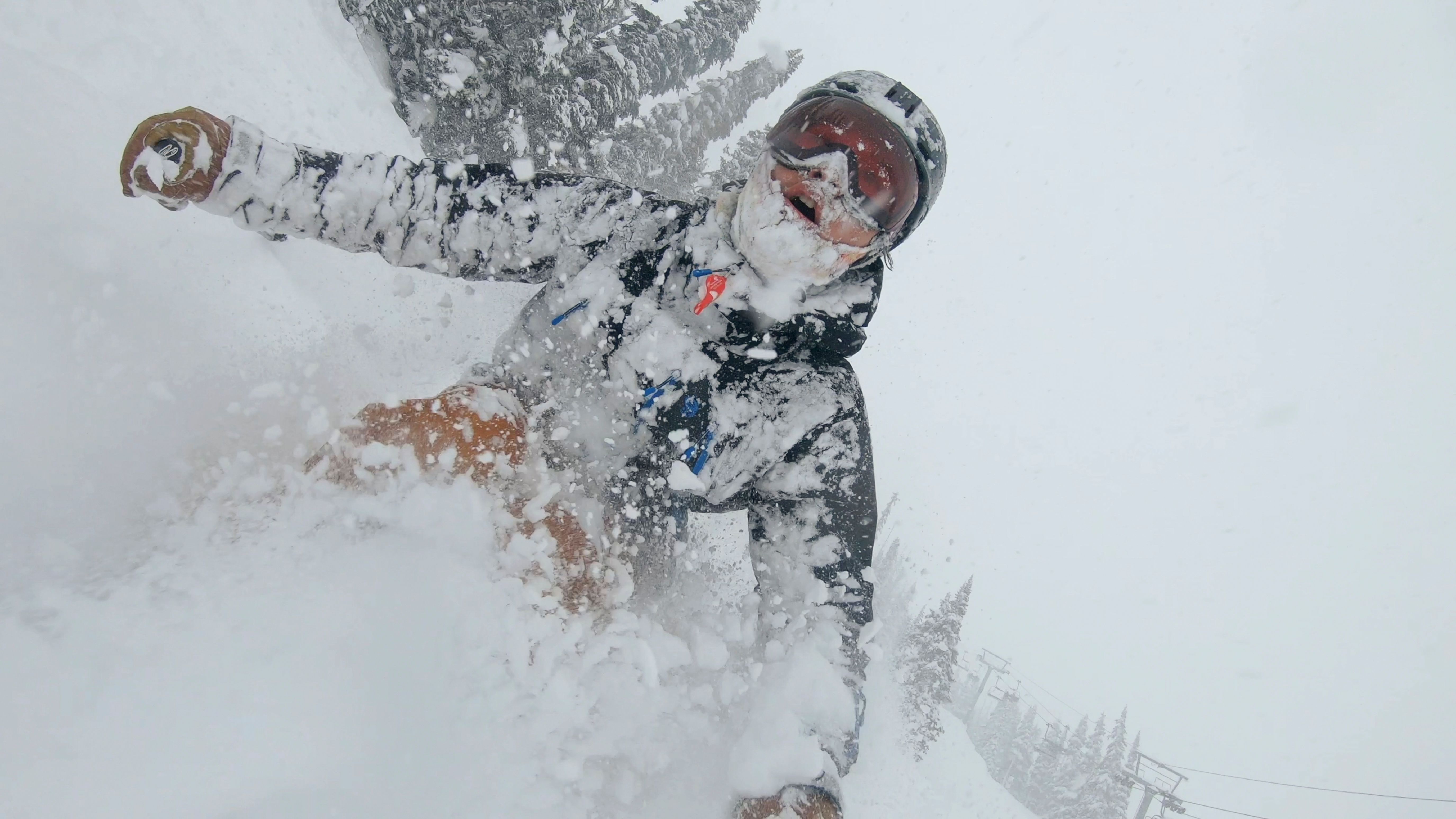 Skier descends snow slope through deep powder snow