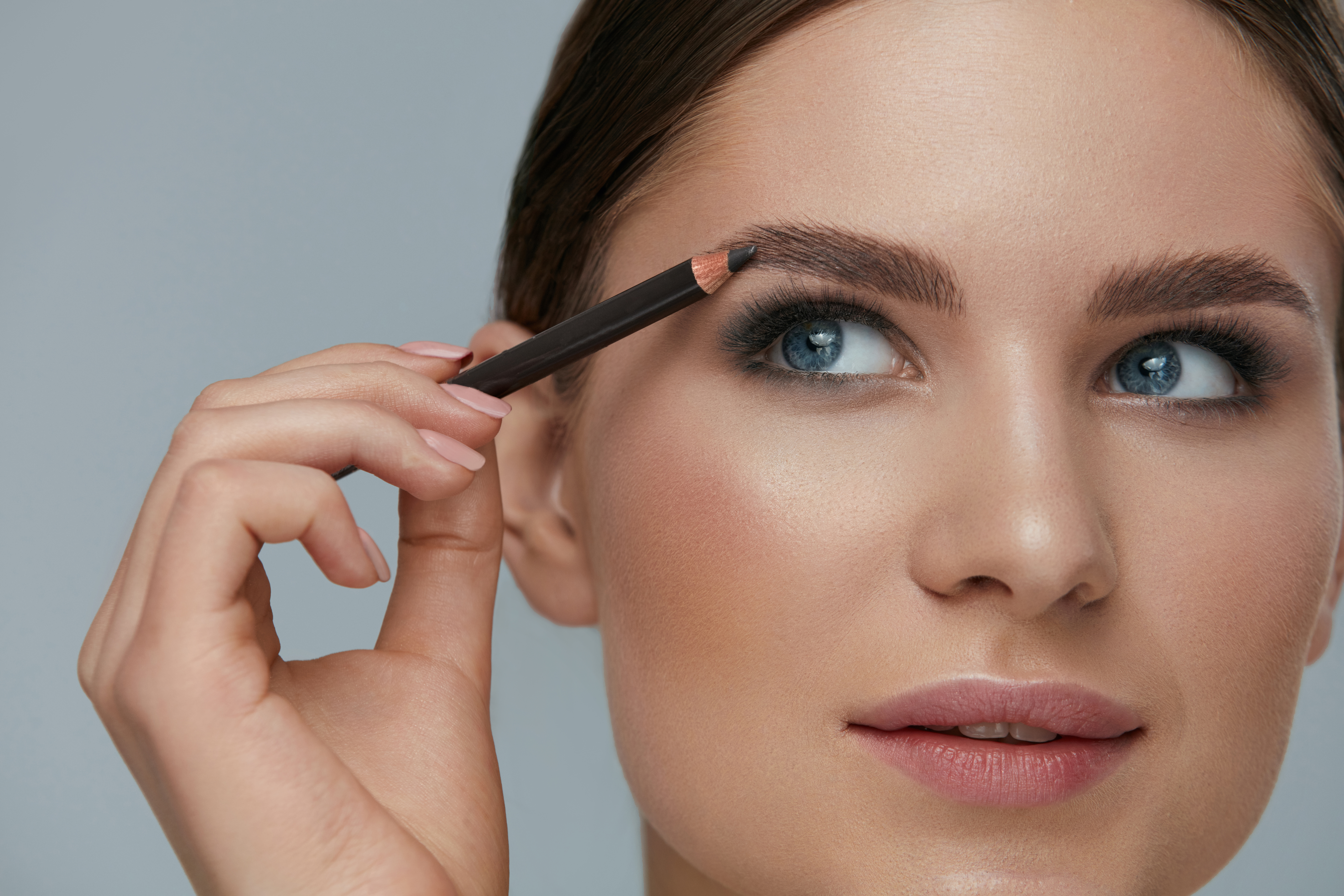 Beauty makeup. Woman shaping eyebrow with brow pencil closeup