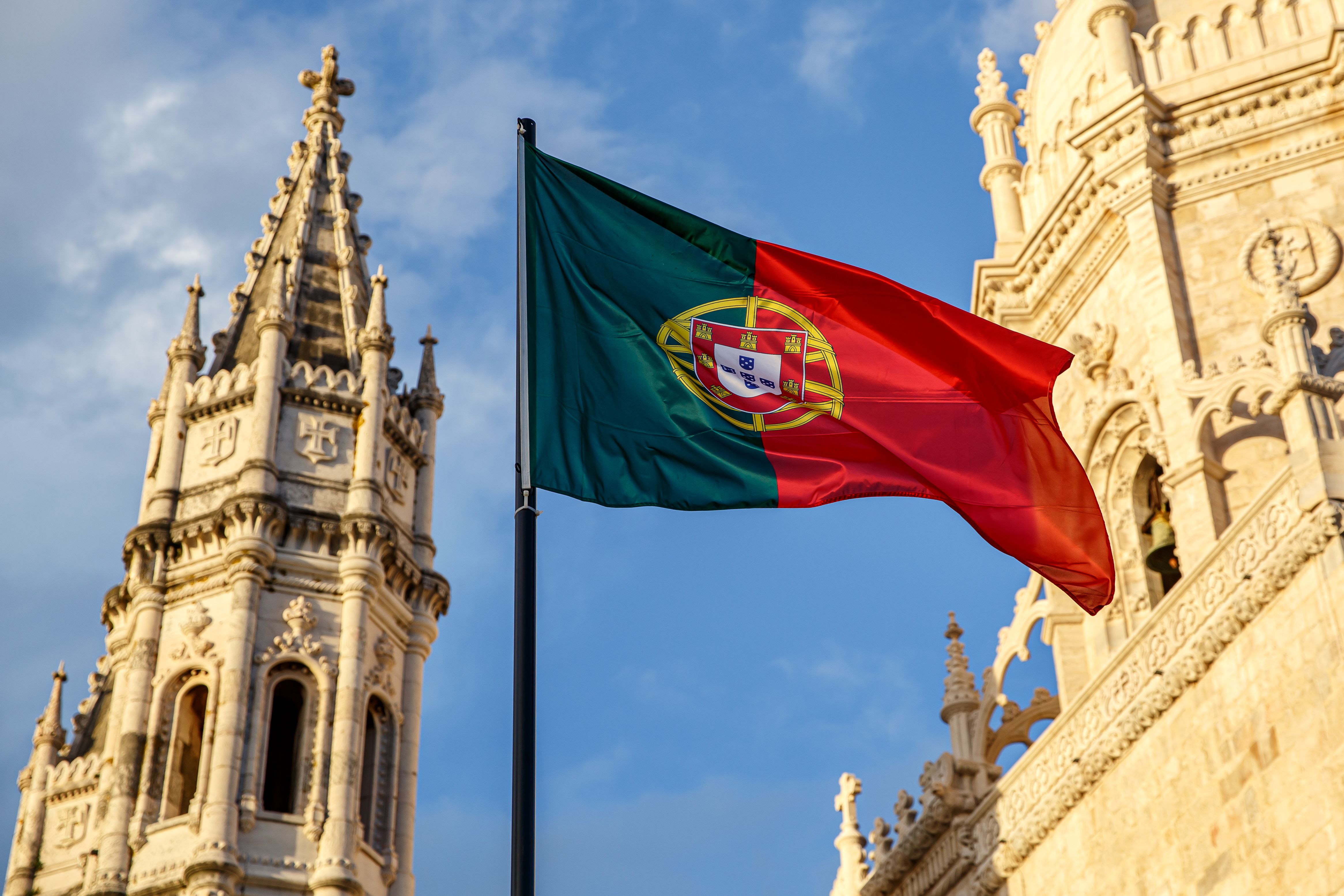 Portuguese flag waving in front of a blue sky and monastery. Portuguese flag waving in front of a blue sky and monastery.