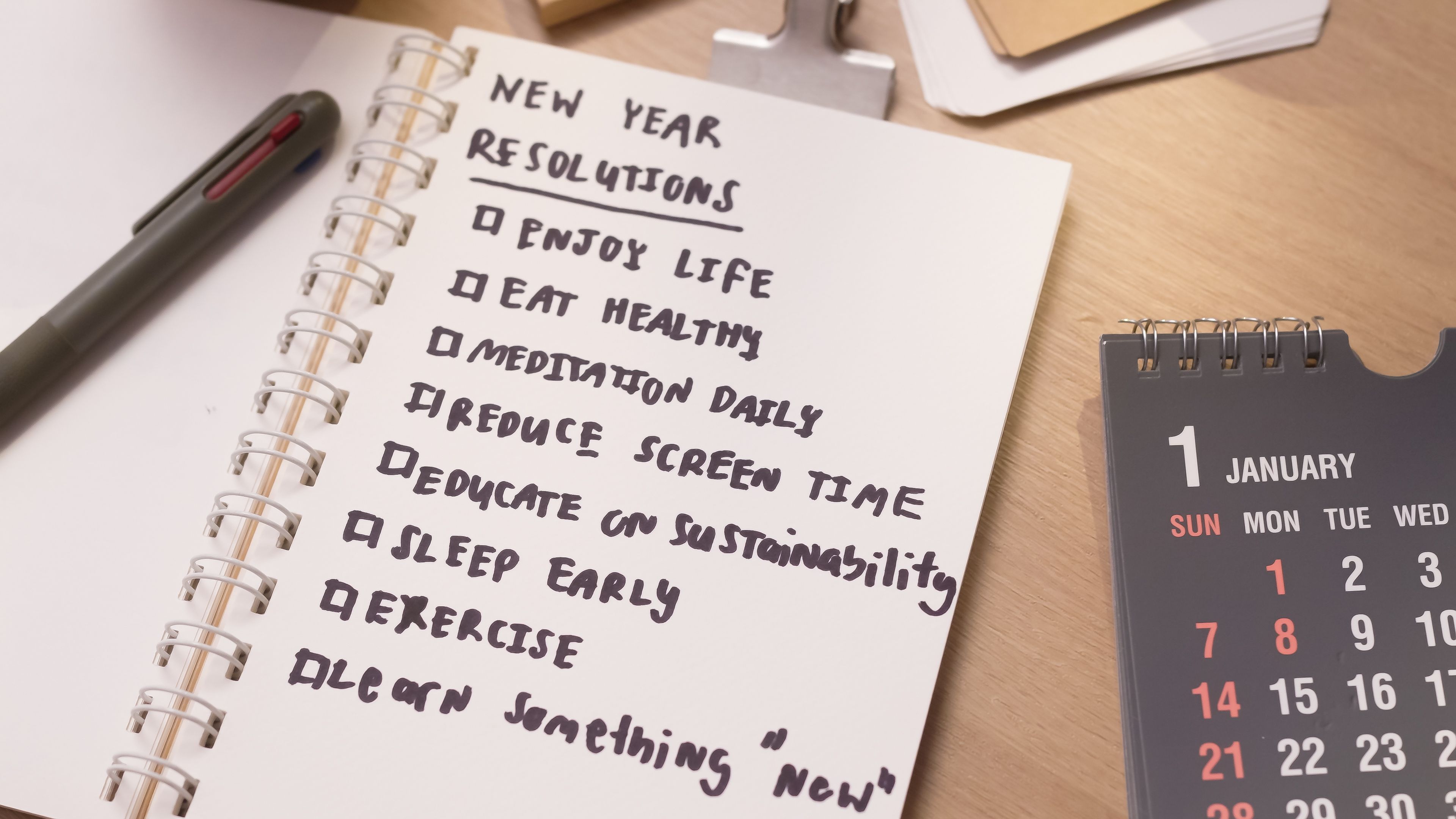 Close up human hand writing New year Resolutions Plans on white paper notebook planning Goal List for well being ,Beginning the new life and enjoy life