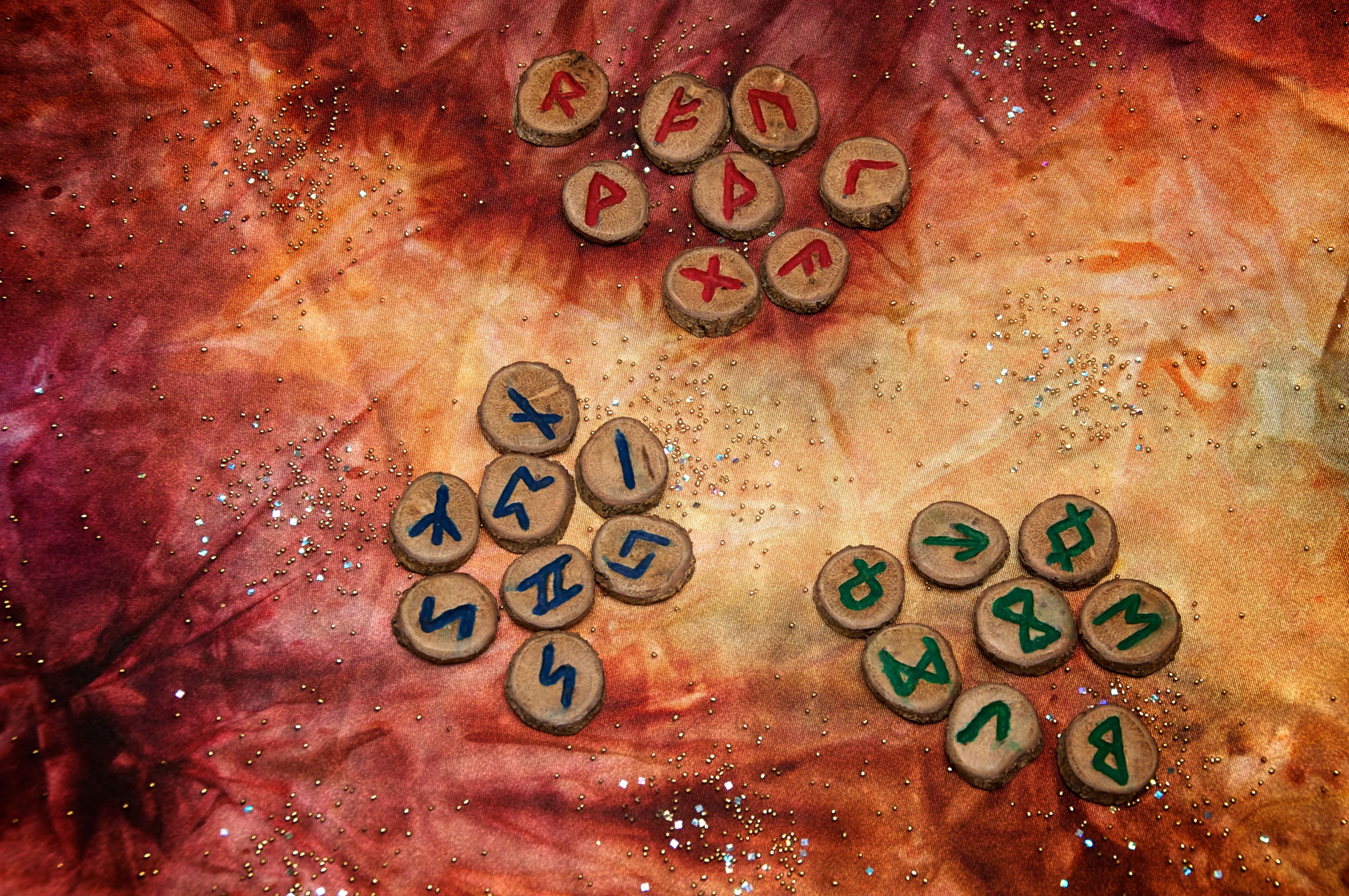 three sets of fortune telling runes on colorful mystical cloth