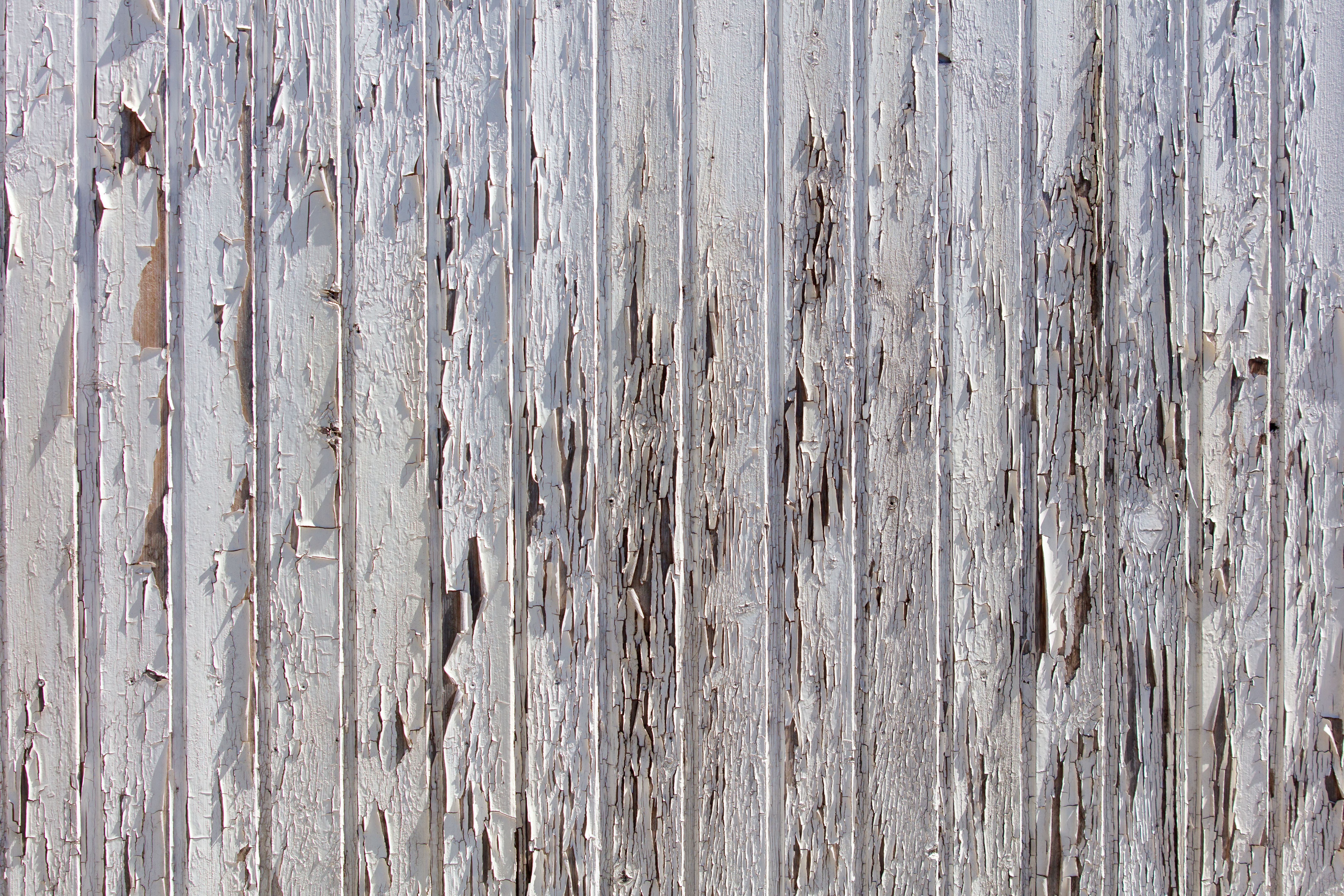 A wooden fence with peeling paint and a lot of damage