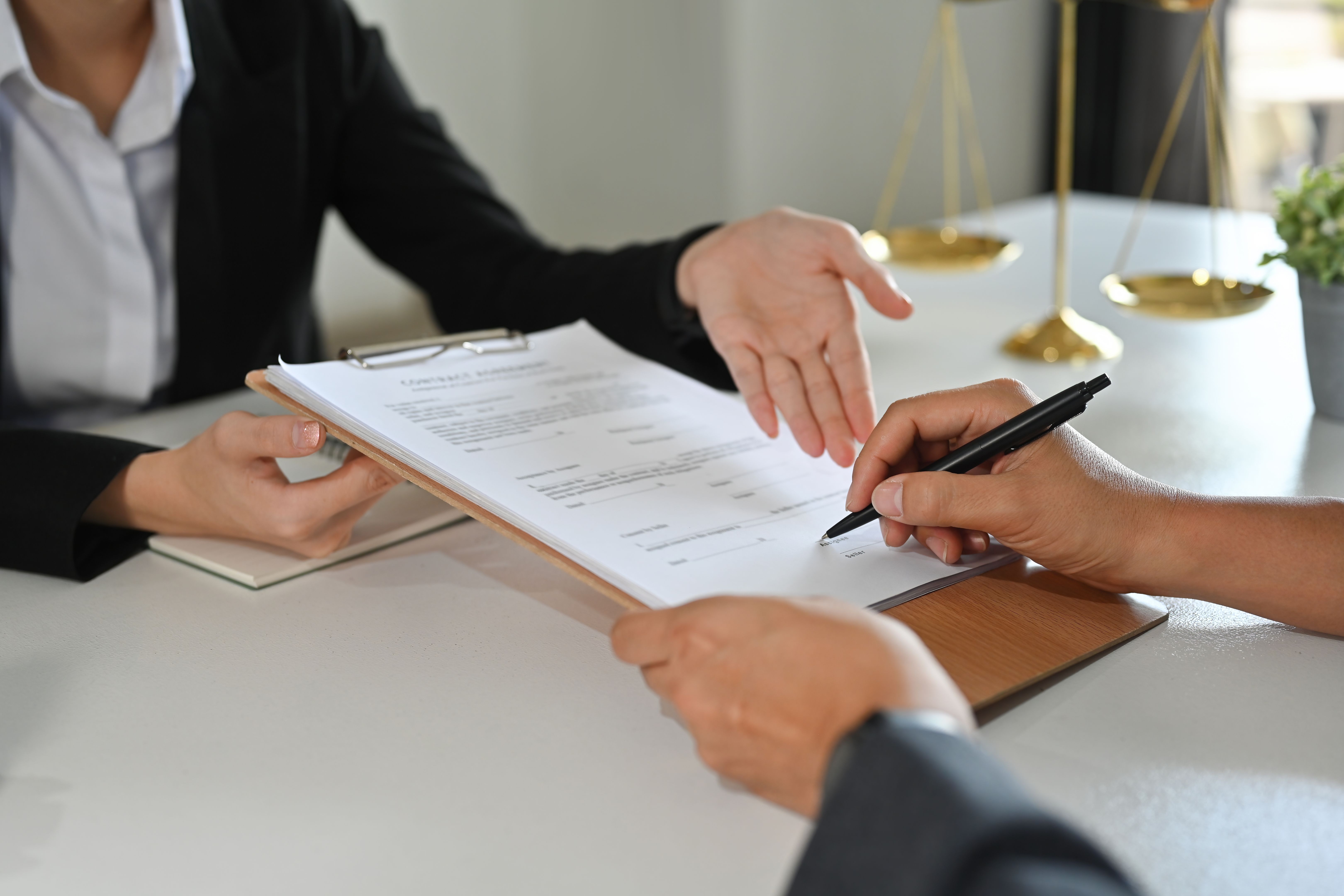 Cropped view of client signing contract or legal papers with lawyer. Law services concept. Cropped view of client signing contract or legal papers with lawyer. Law services concept.