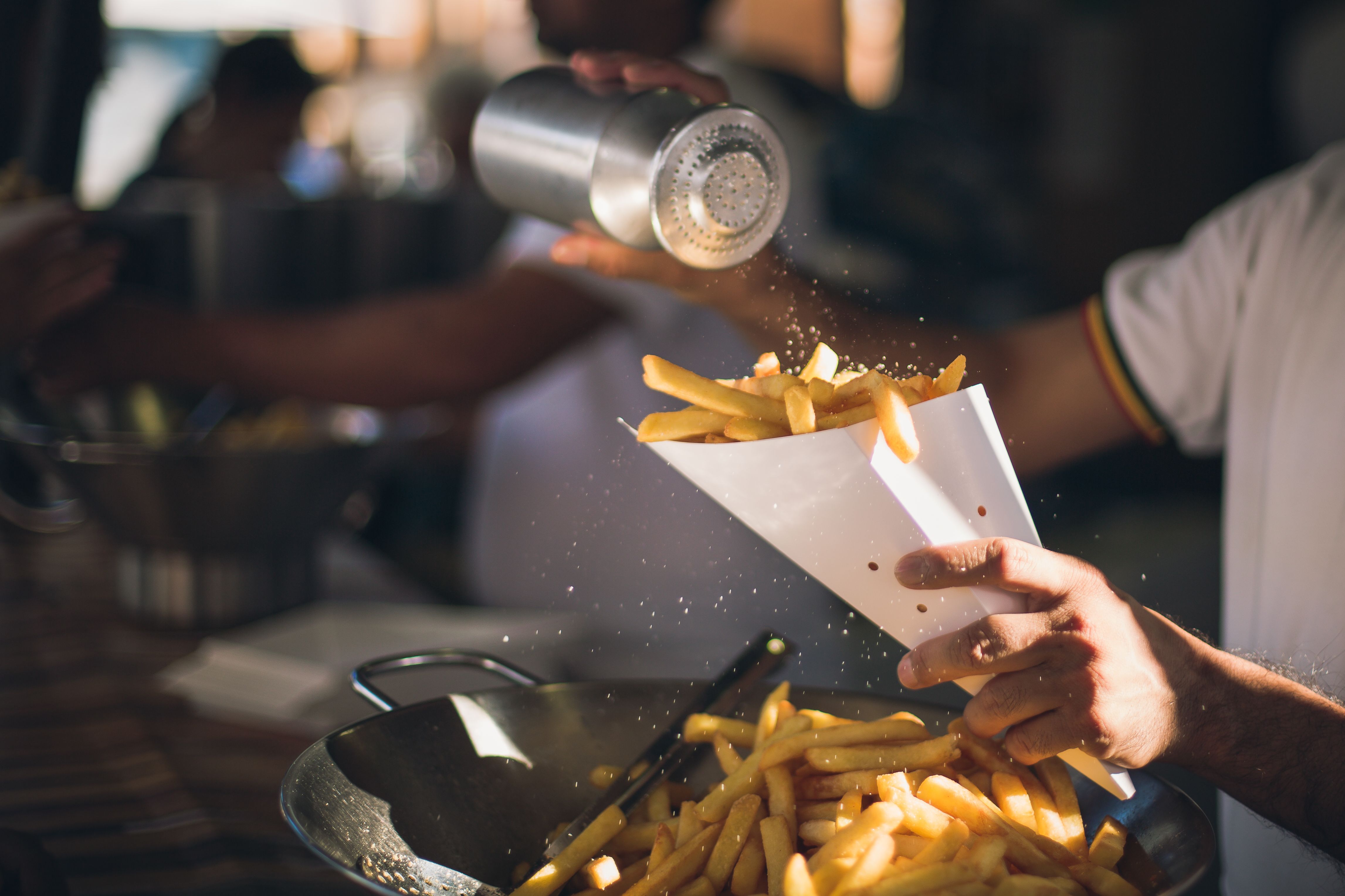 Midsection Of Man Dusting Salt On French Fries
