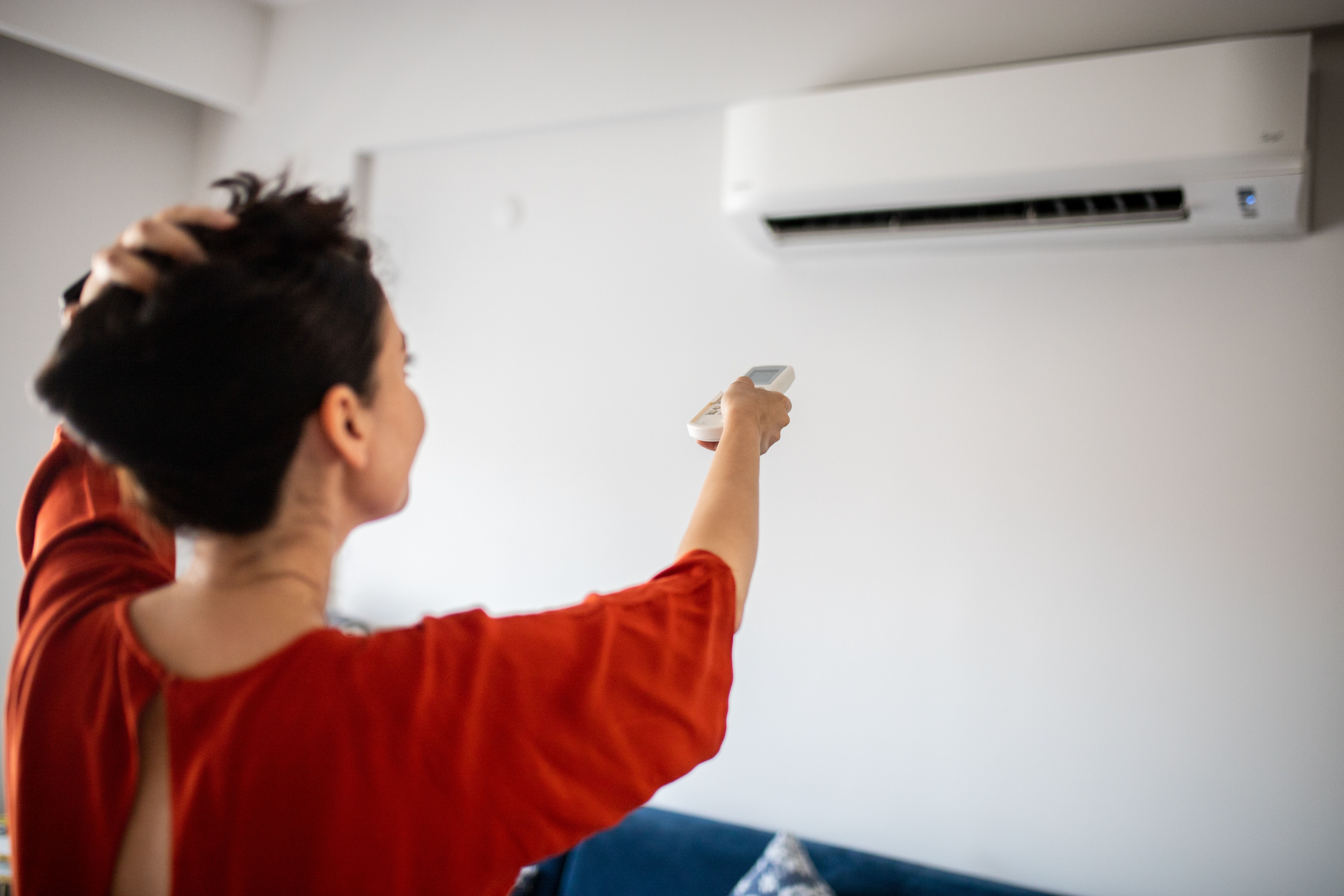 Woman switching on air conditioner Woman switching on air conditioner