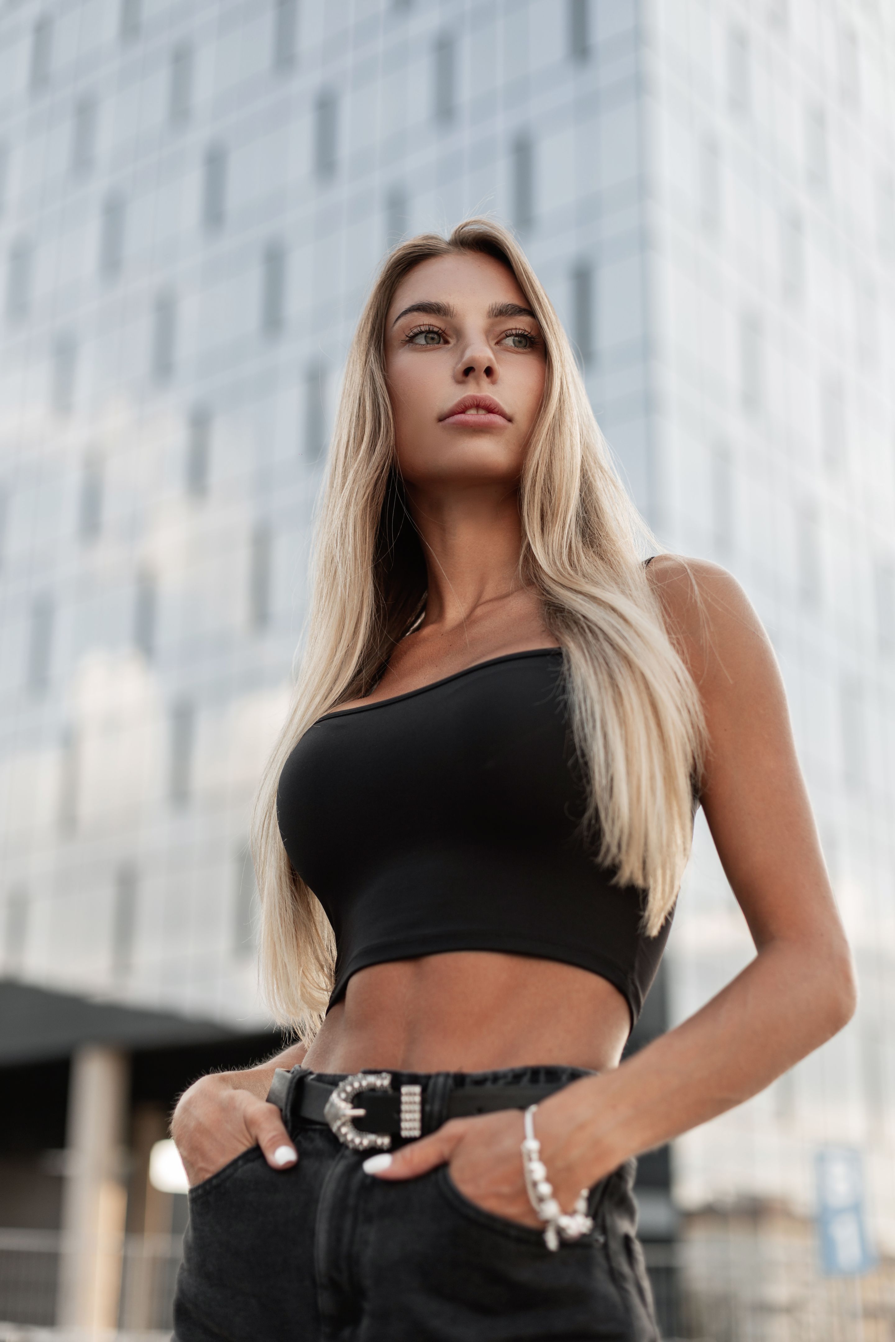 beautiful woman in fashionable black jeans with a belt and a black blank T-shirt with a jewelry bracelet on arm stands on the street beautiful woman in fashionable black jeans with a belt and a black blank T-shirt with a jewelry bracelet on arm stands on the street