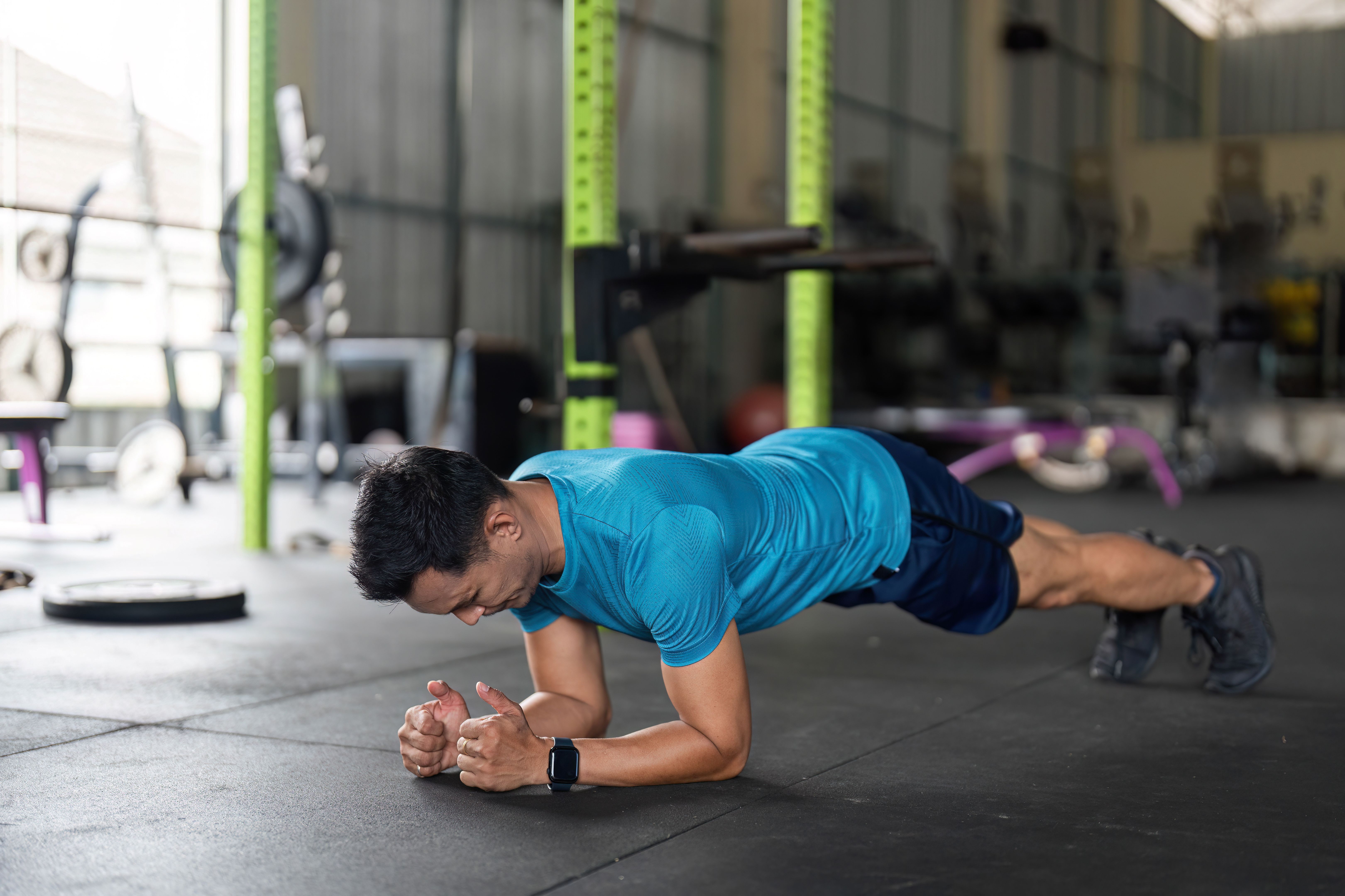 Fitness Strength Training. Male athlete performing a plank exercise on gym floor.