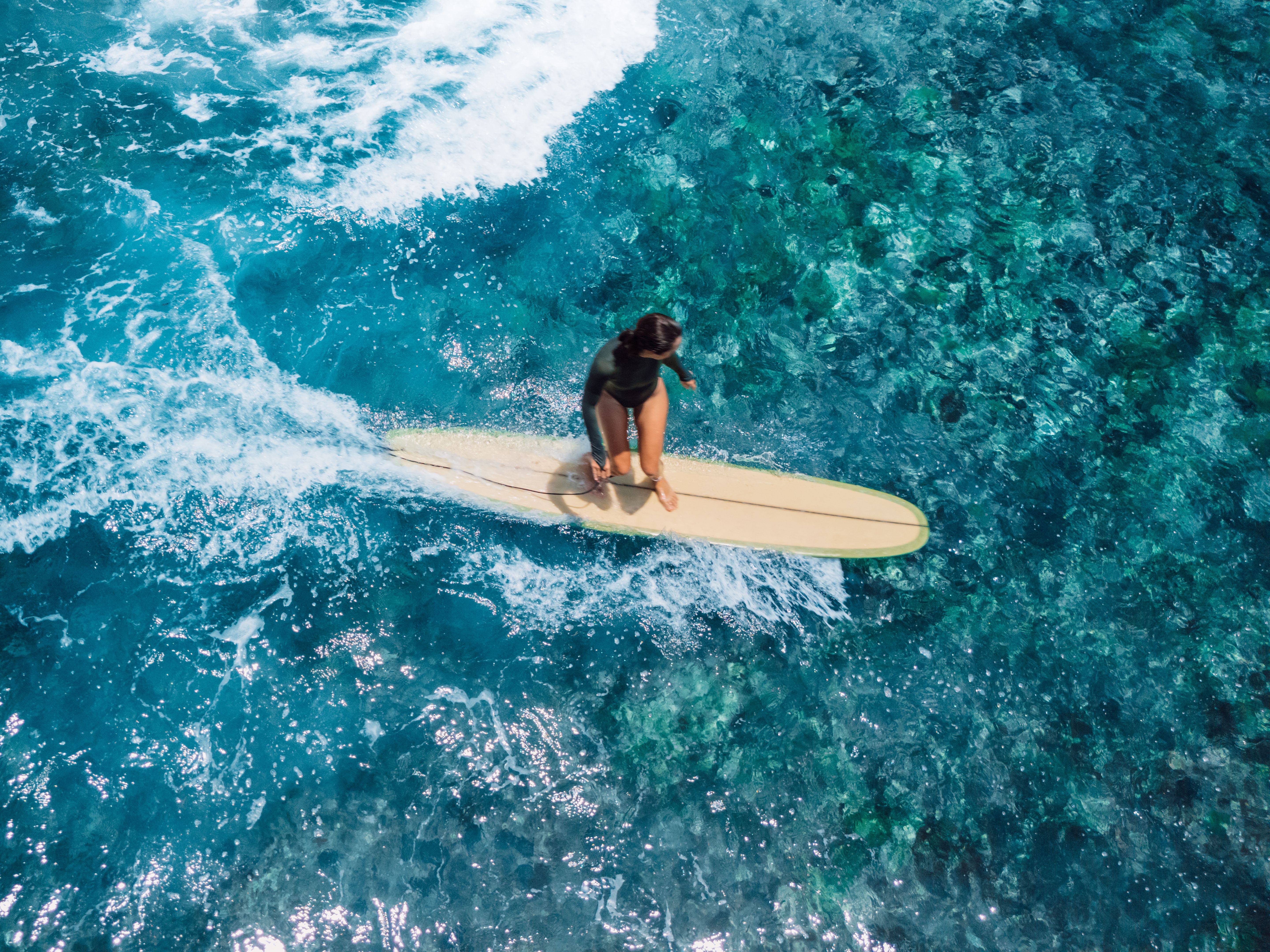 Woman rides on longboard on ocean wave. Drone view of woman during surfing Woman rides on longboard on ocean wave. Drone view of woman during surfing