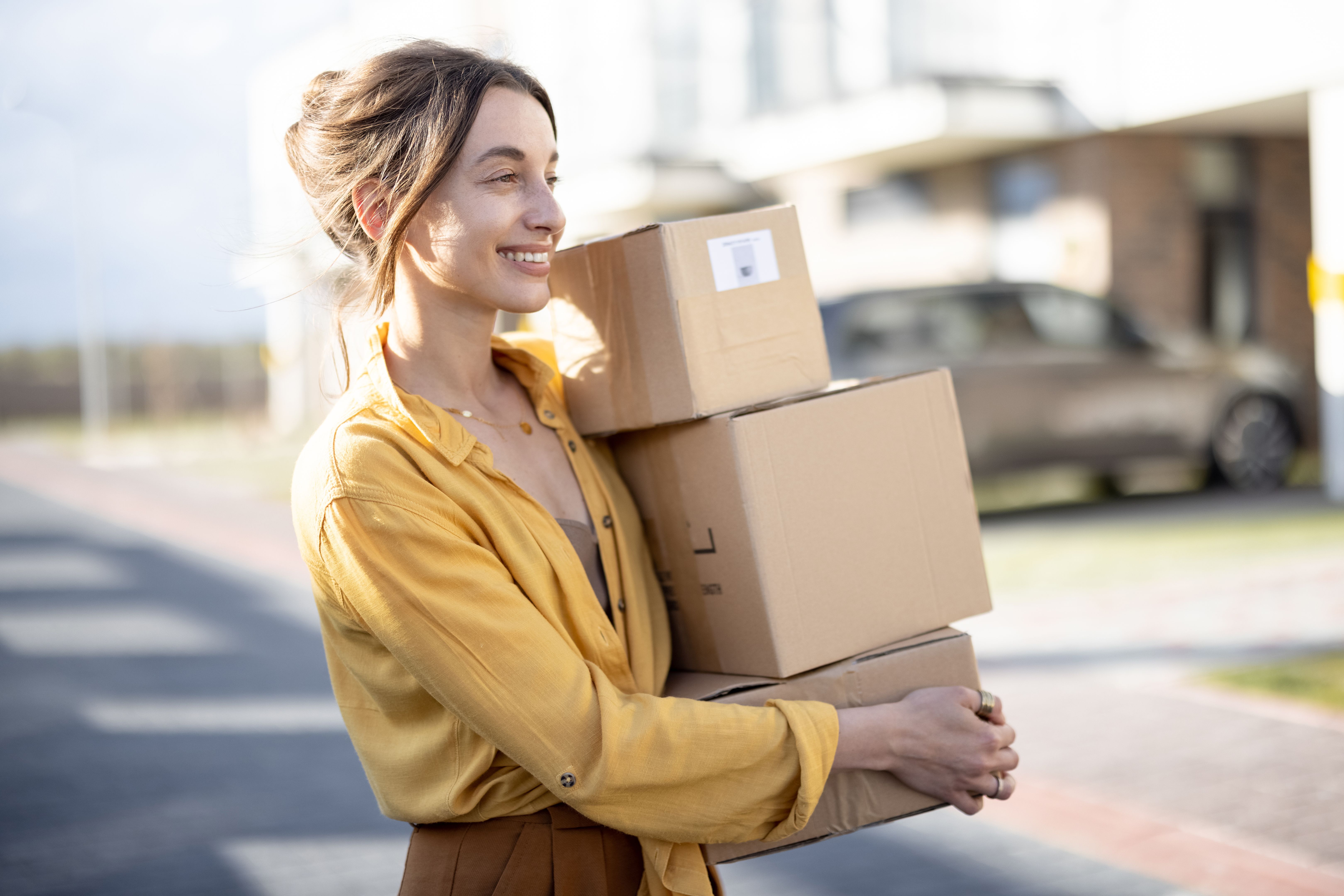 Woman holding parcels on the street in front of the house