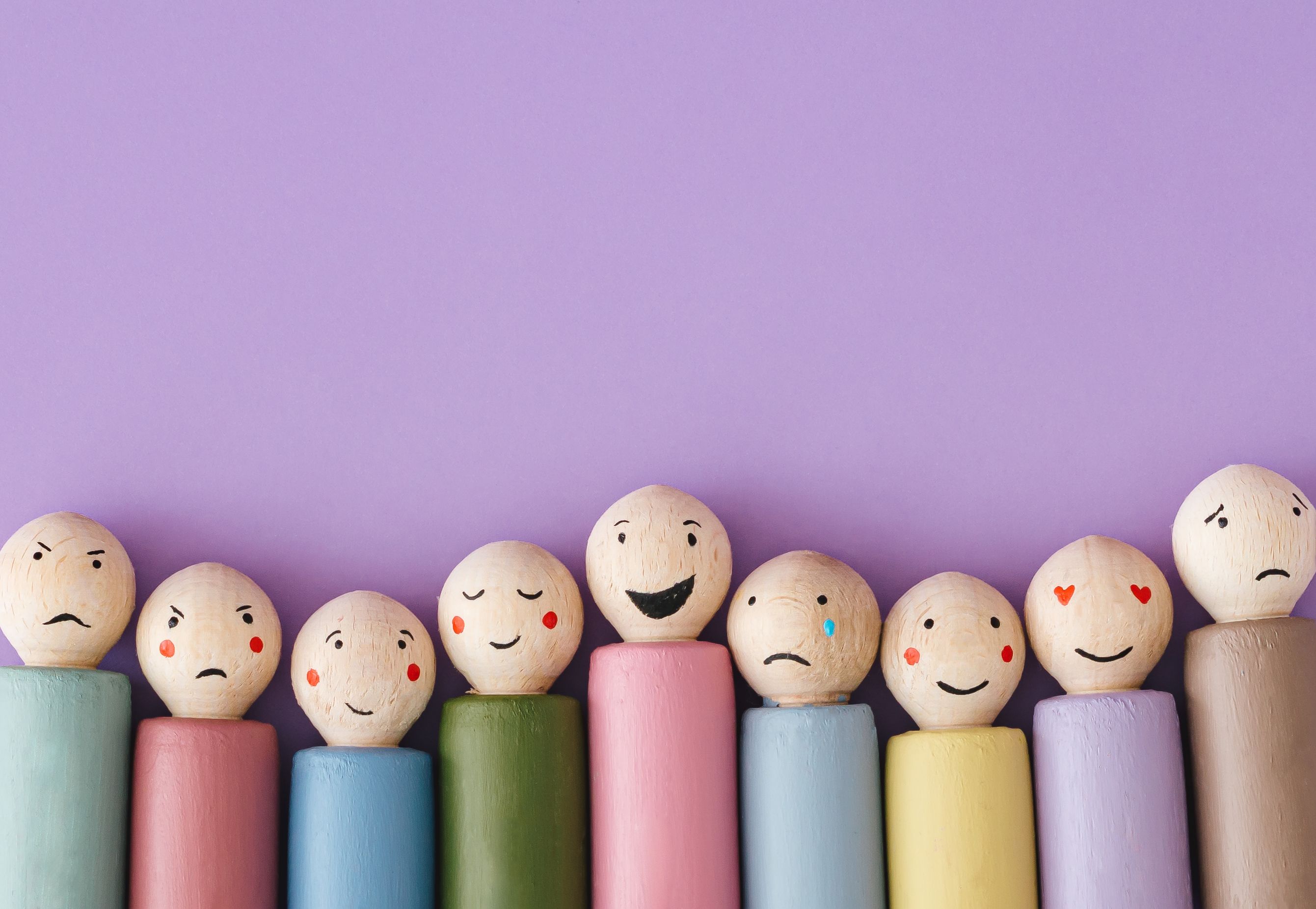 Image of different emotions on wooden peg dolls on purple background with copy space. Flat lay, top of view. Image of different emotions on wooden peg dolls on purple background with copy space. Flat lay, top of view.