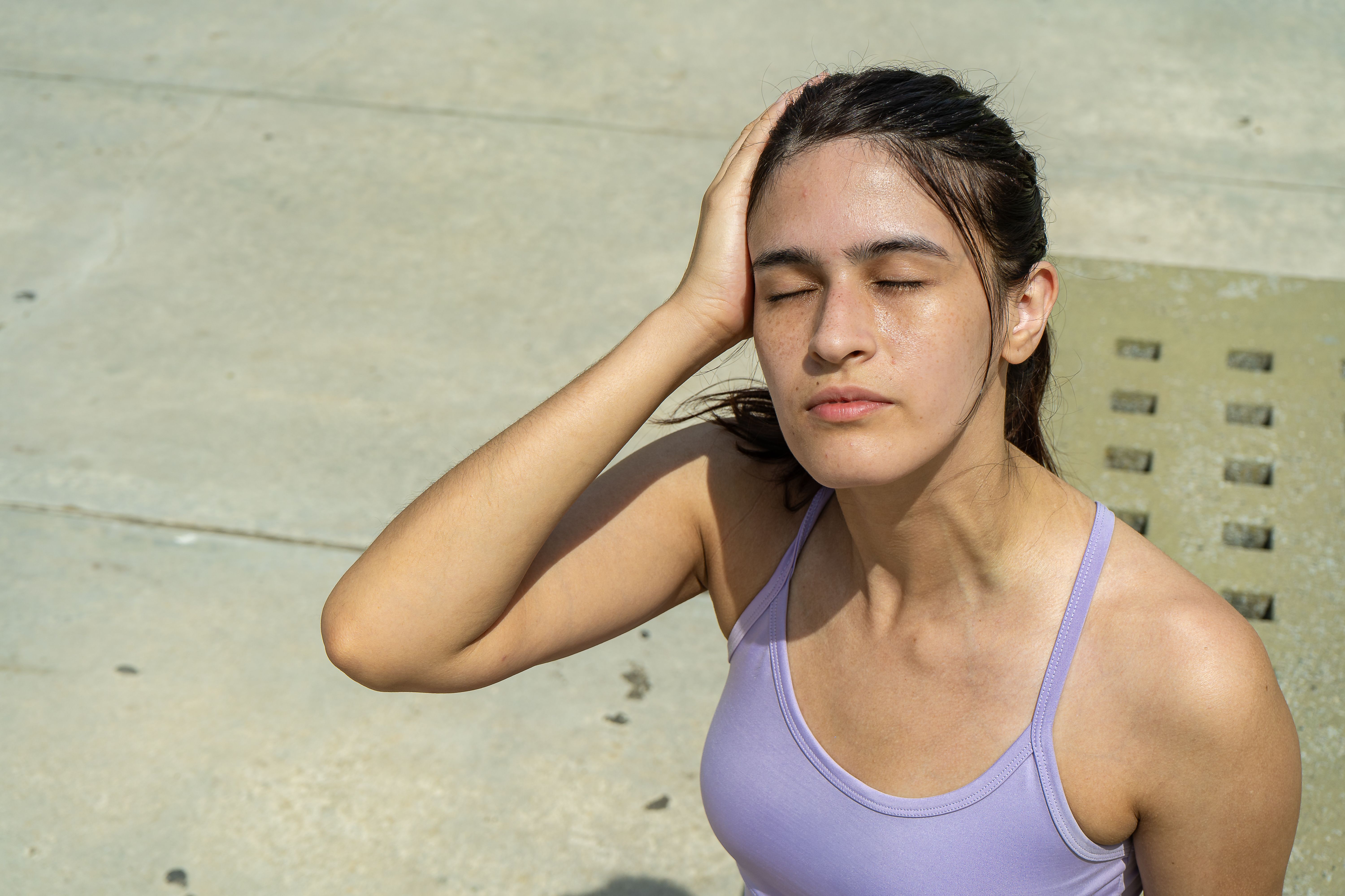 Young sporty woman suffering from heatstroke outdoors after exercising