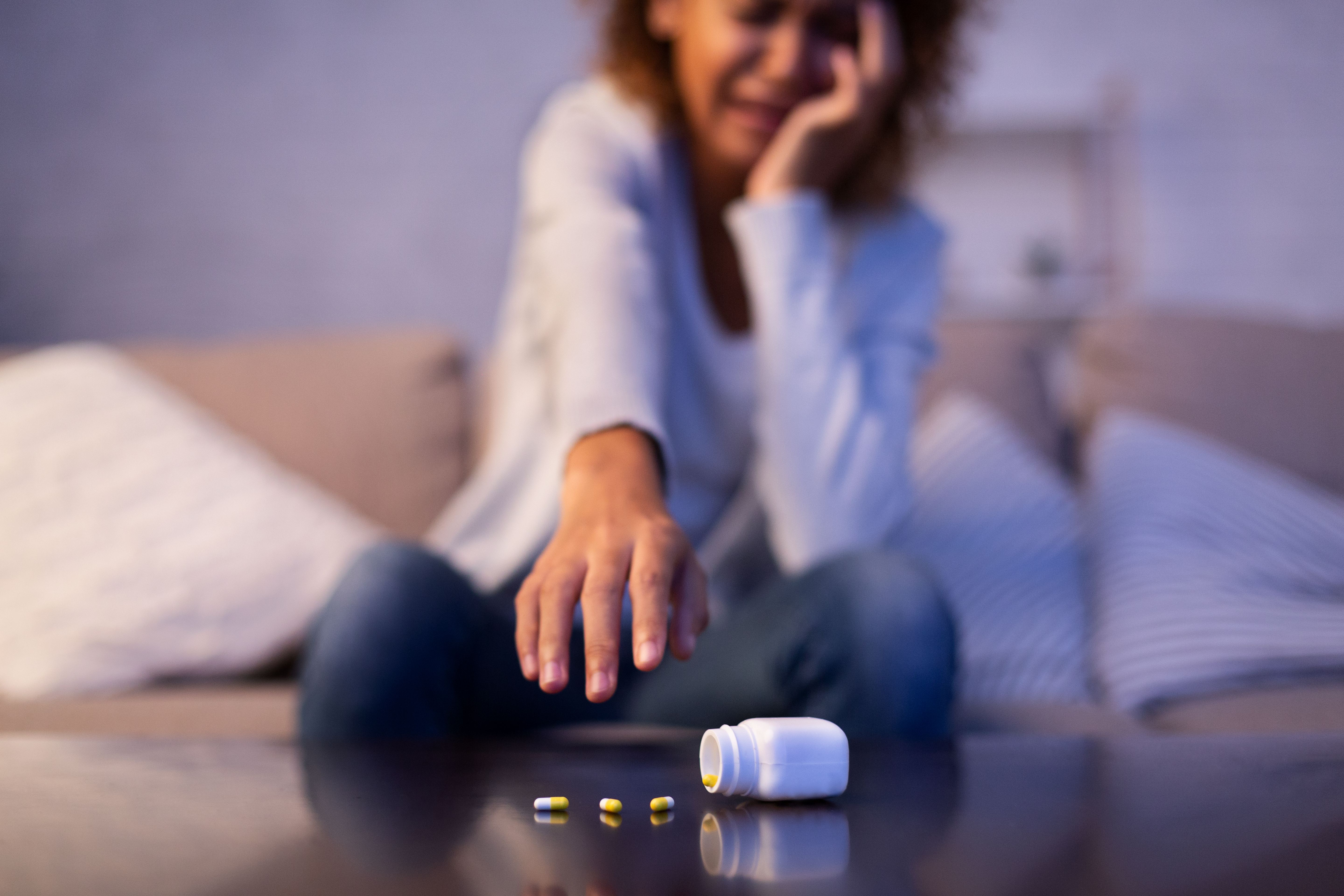 Depressed woman catching antidepressant pills and crying