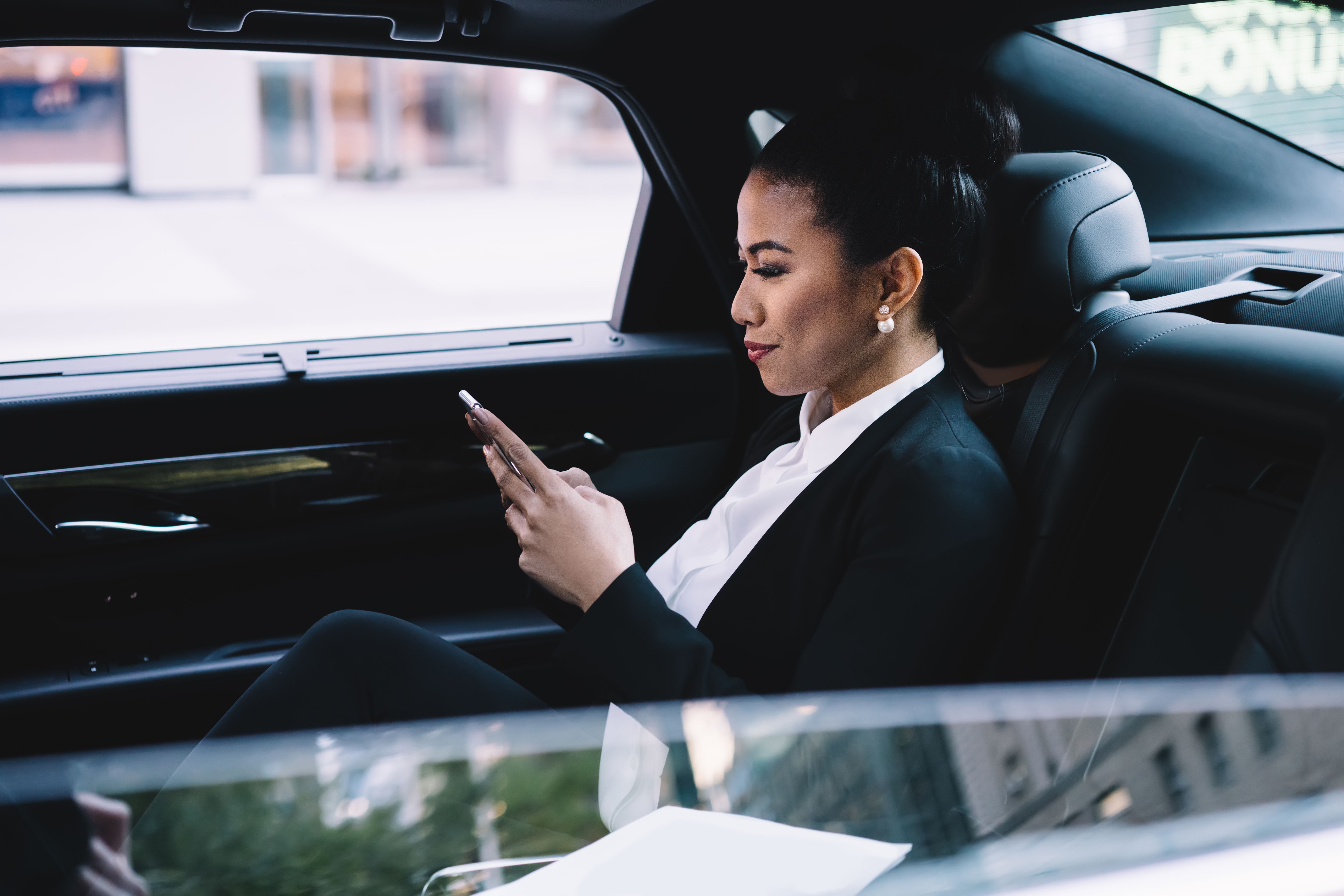 Pensive ethnic business lady using smartphone in car Pensive ethnic business lady using smartphone in car