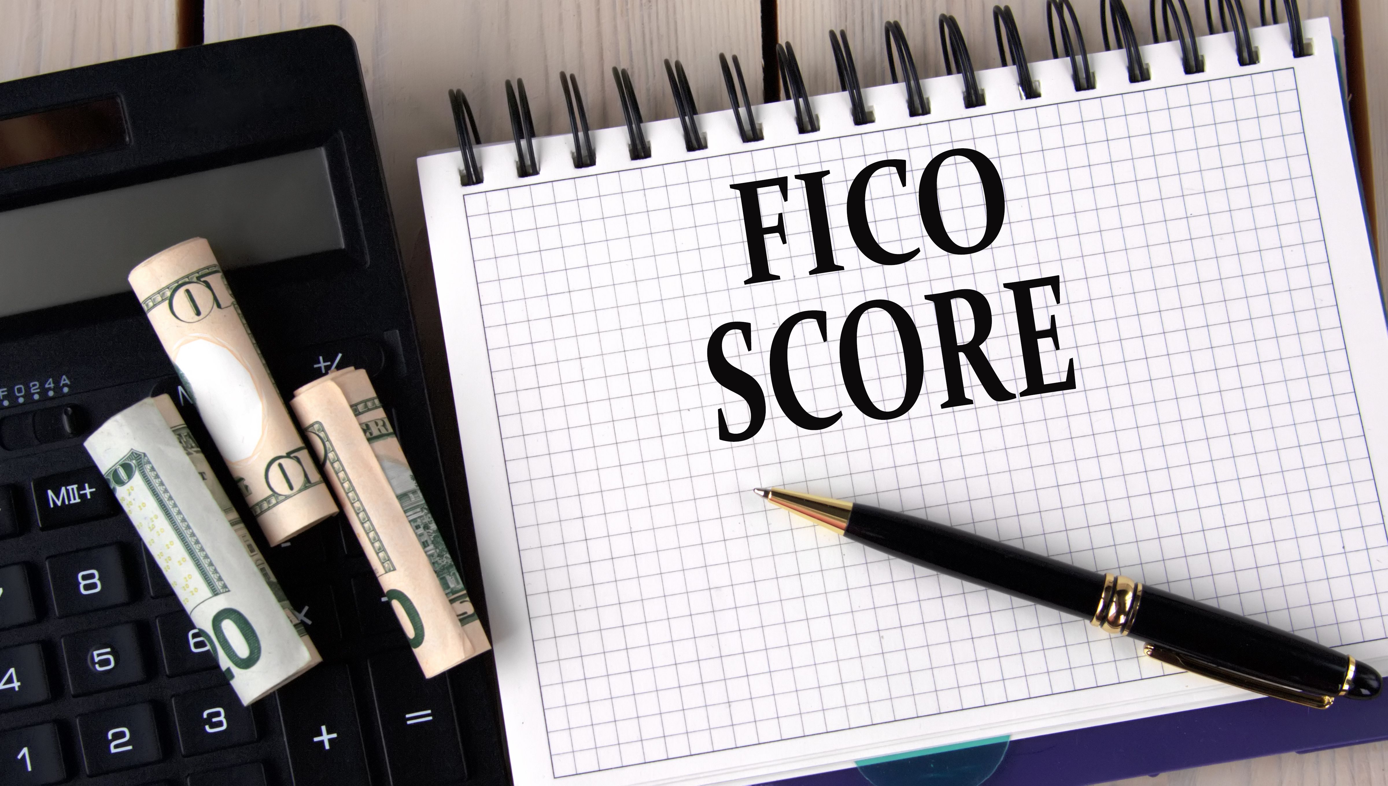 FICO SCORE - words in a notebook on the background of a calculator and banknotes FICO SCORE - words in a notebook on the background of a calculator and banknotes