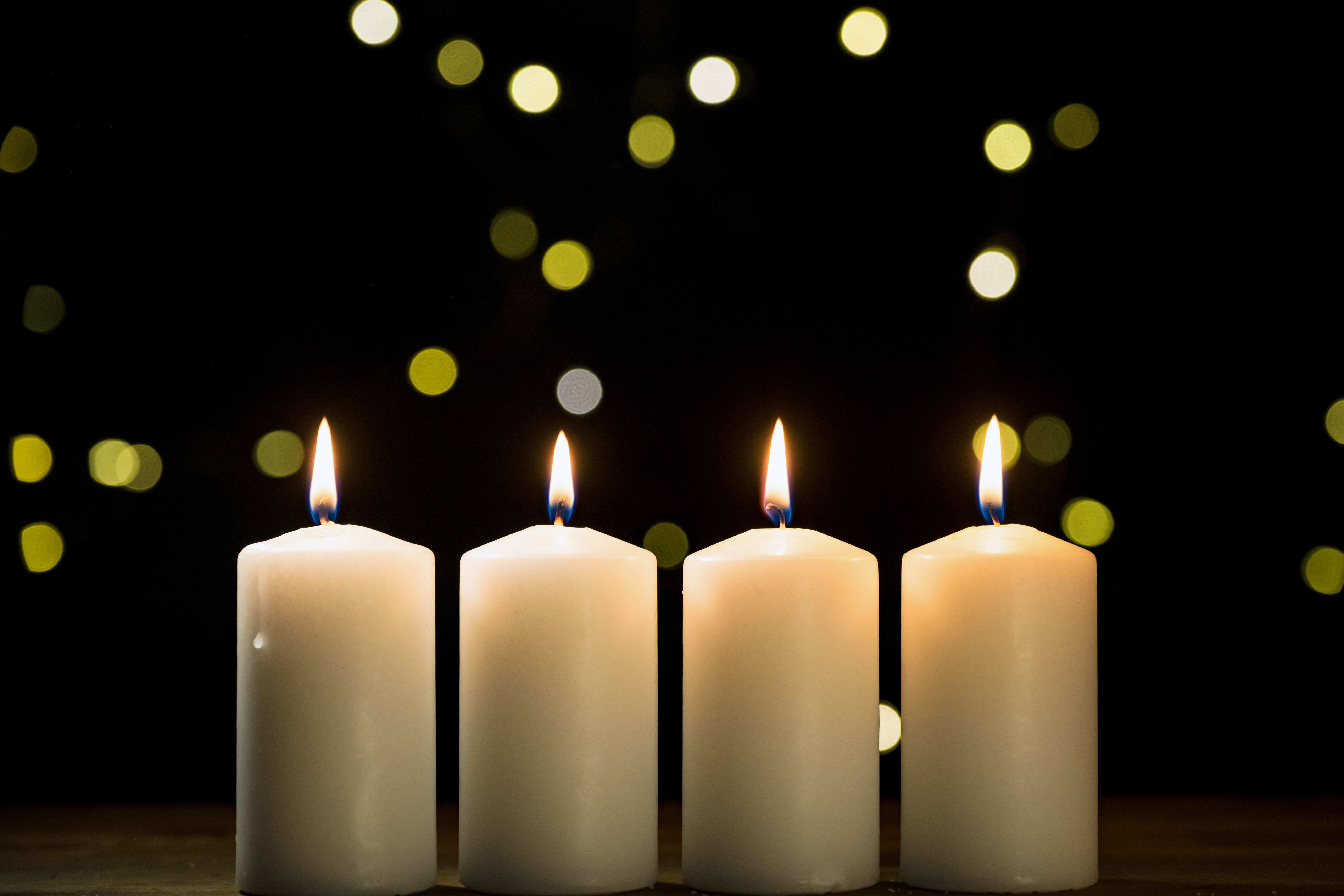 Four burning white candles on a festive black background with golden decoration Four burning white candles on a festive black background with golden decoration