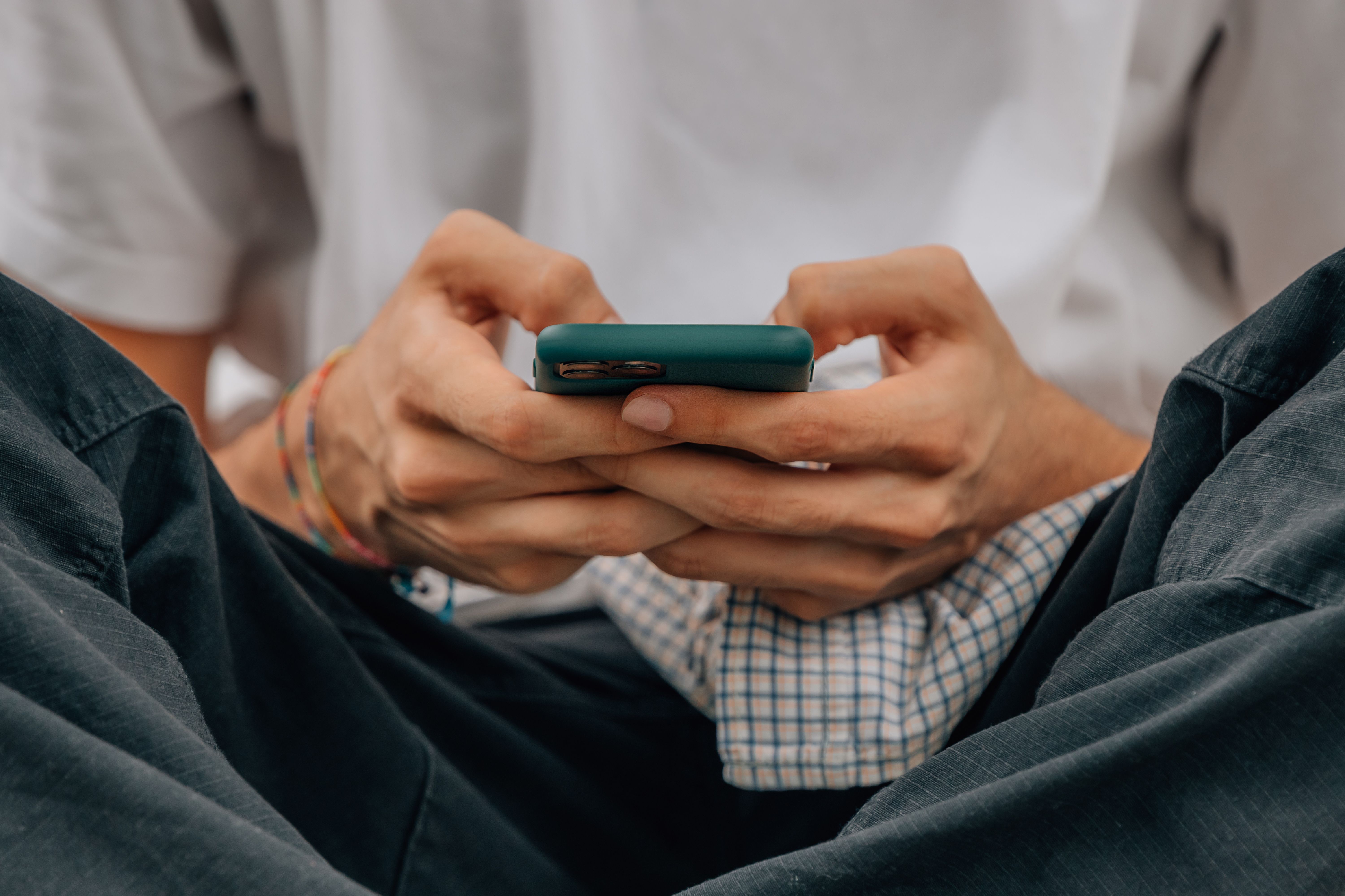 Gros plan des mains d’un jeune homme avec un téléphone portable