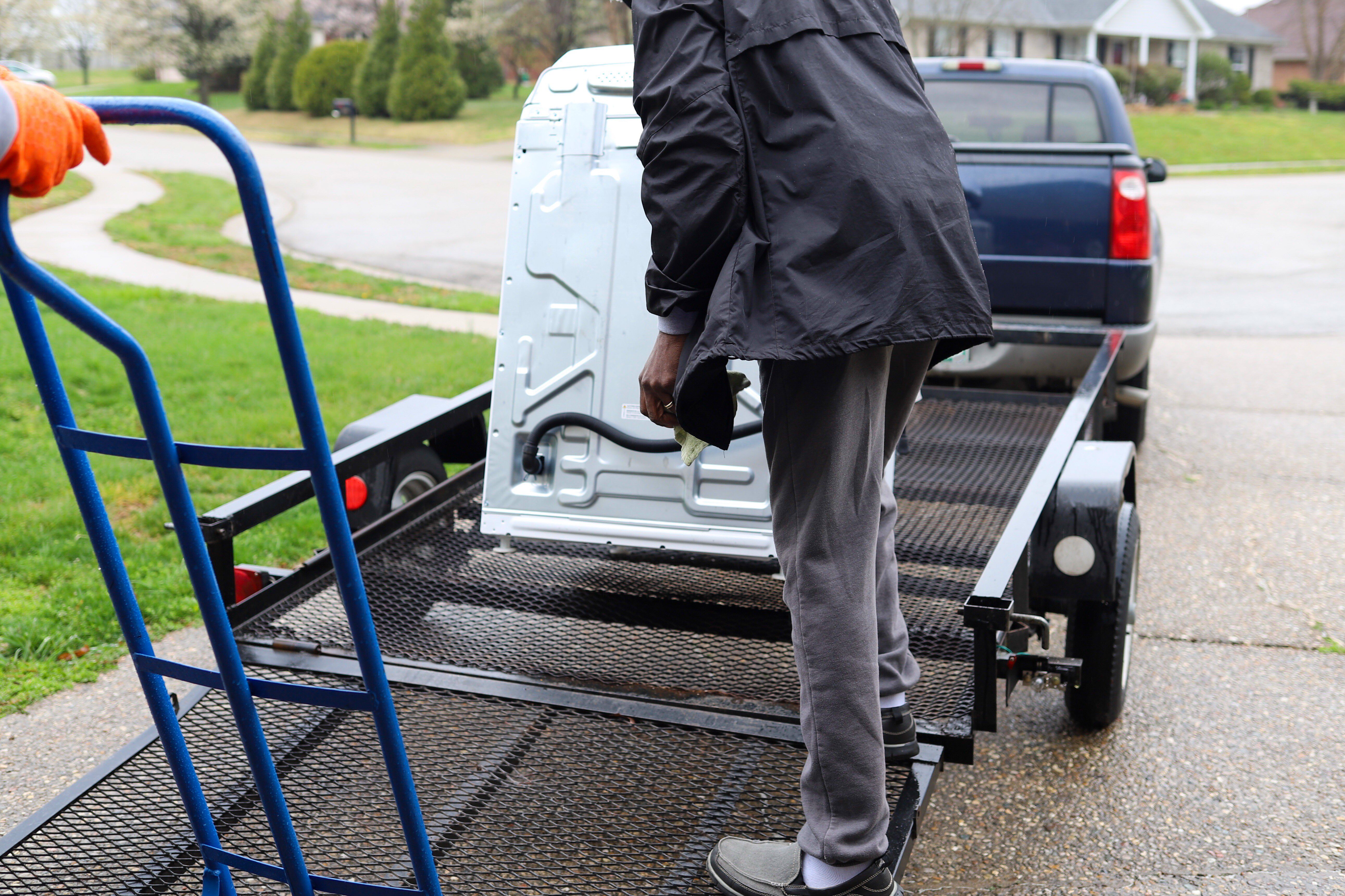 A black African-American man delivering a washing machine on a truck
