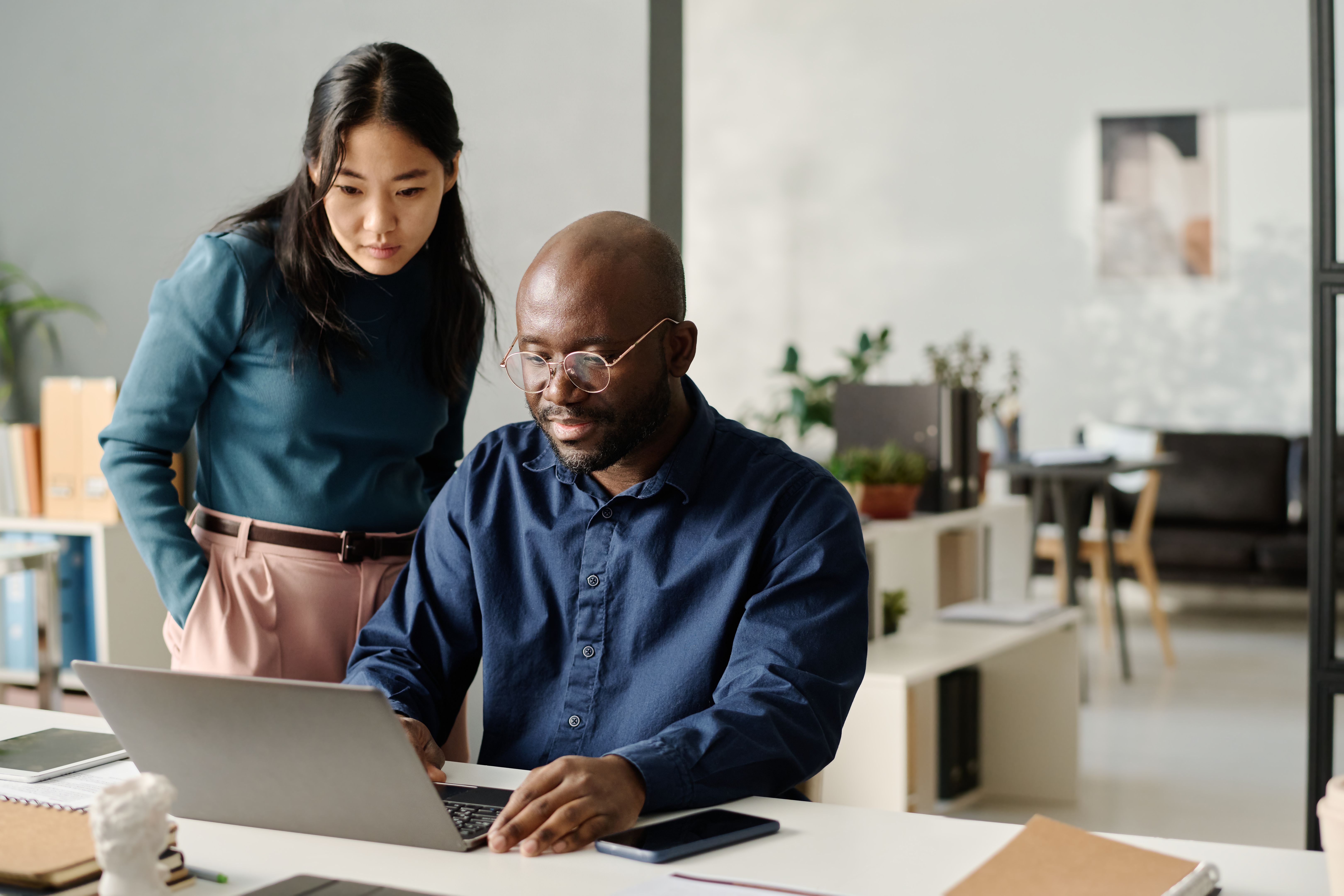 Asian Woman And Black Man Looking At Laptop Screen