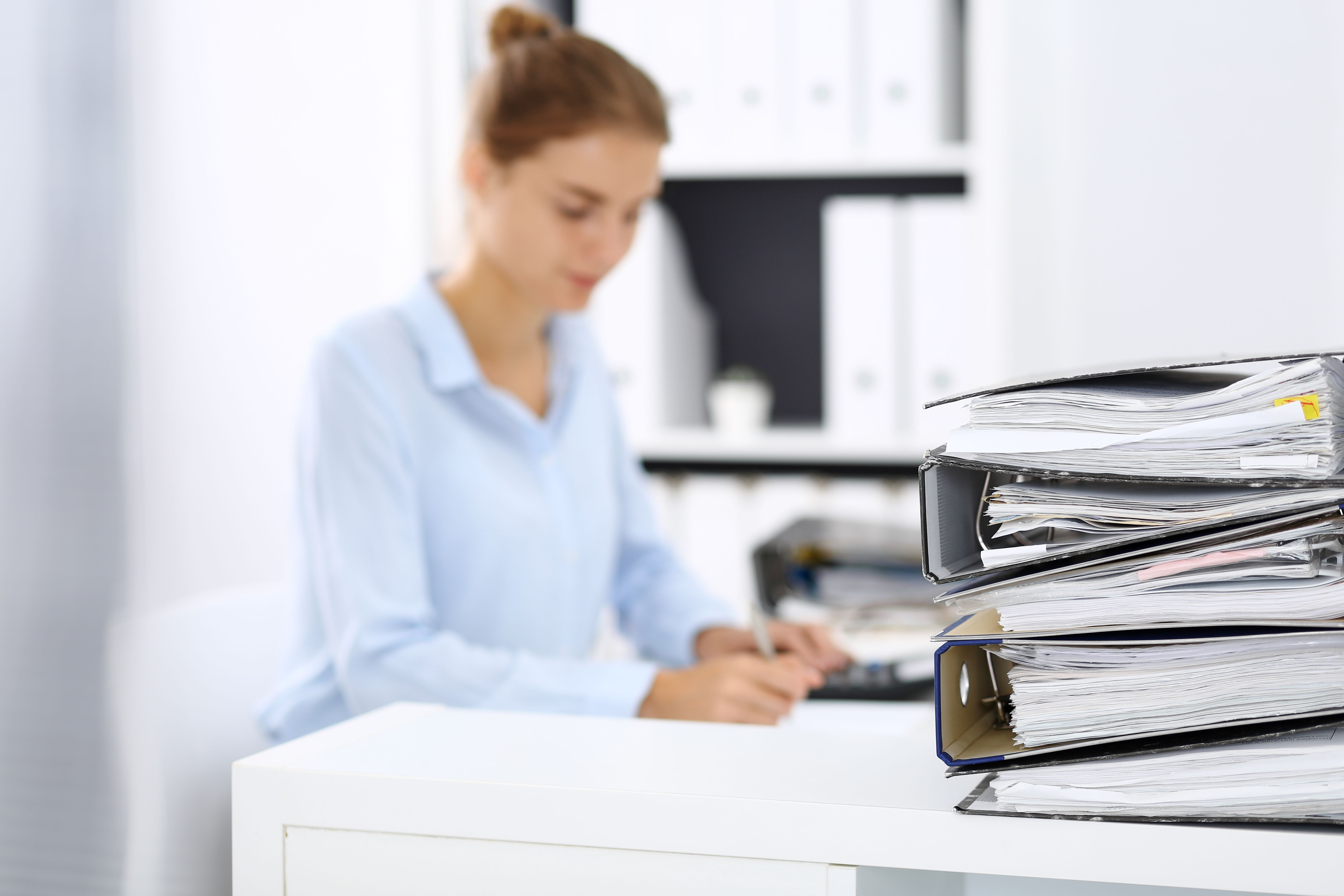 Binders with papers are waiting to be processed by business woman or bookkeeper back in blur. Internal Audit and tax concept