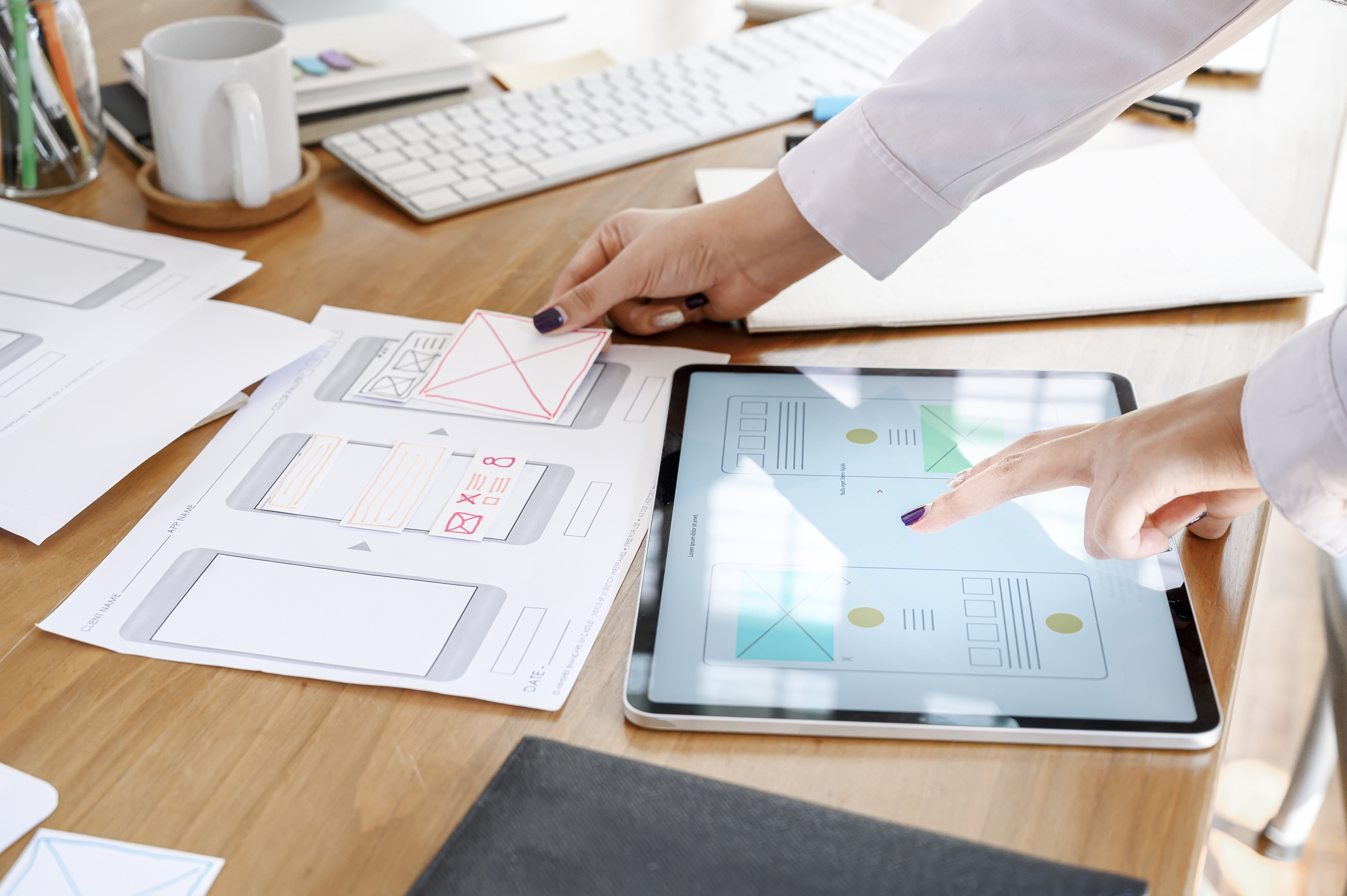 UX designer team using tablet designing smartphone prototype or application layout at office desk.