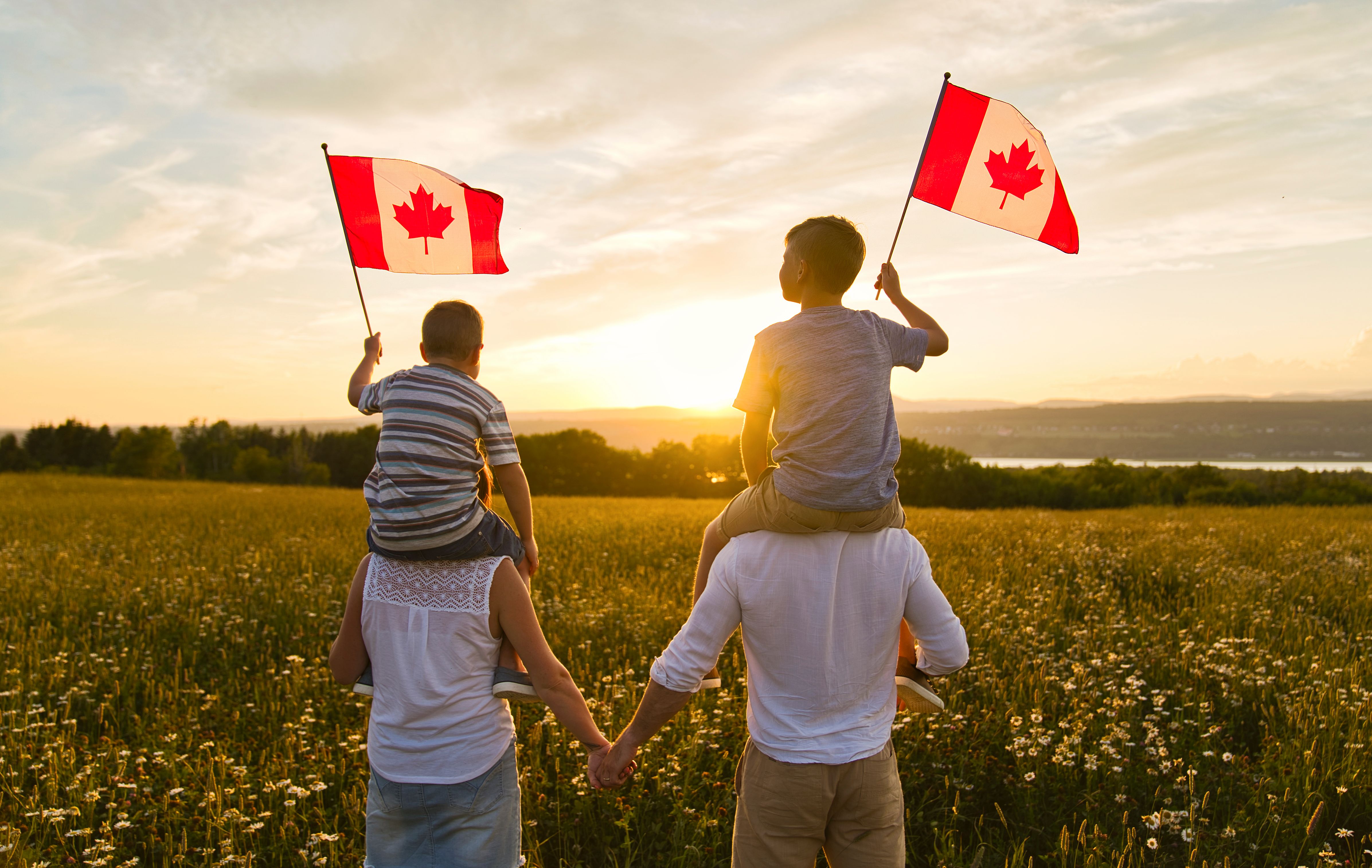 Adorable cute happy Caucasian boys holding Canadian flag on the father shoulder