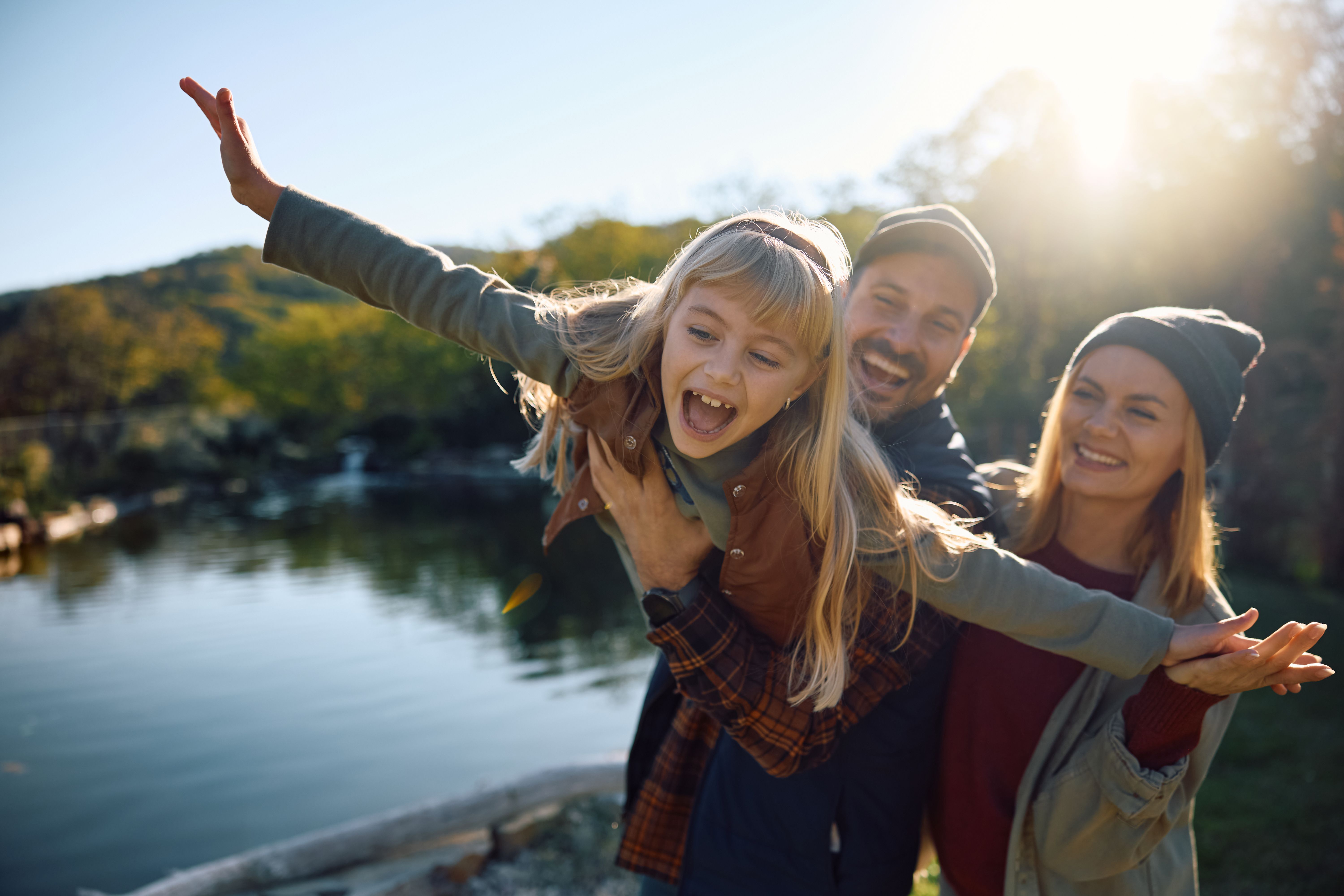 Little girl having fun with her parents in nature during autumn.