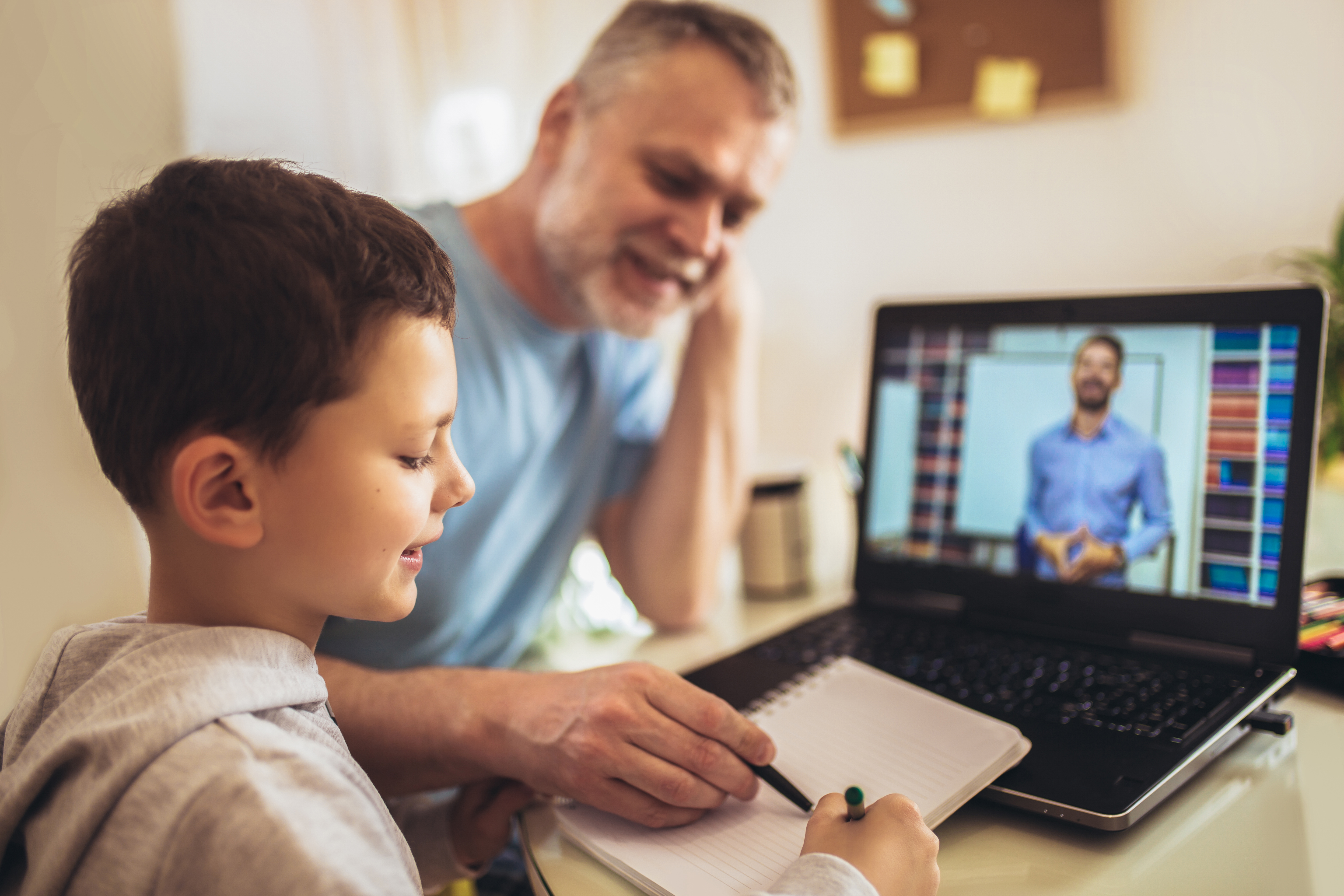 Boy in video conference with teacher on laptop at home.