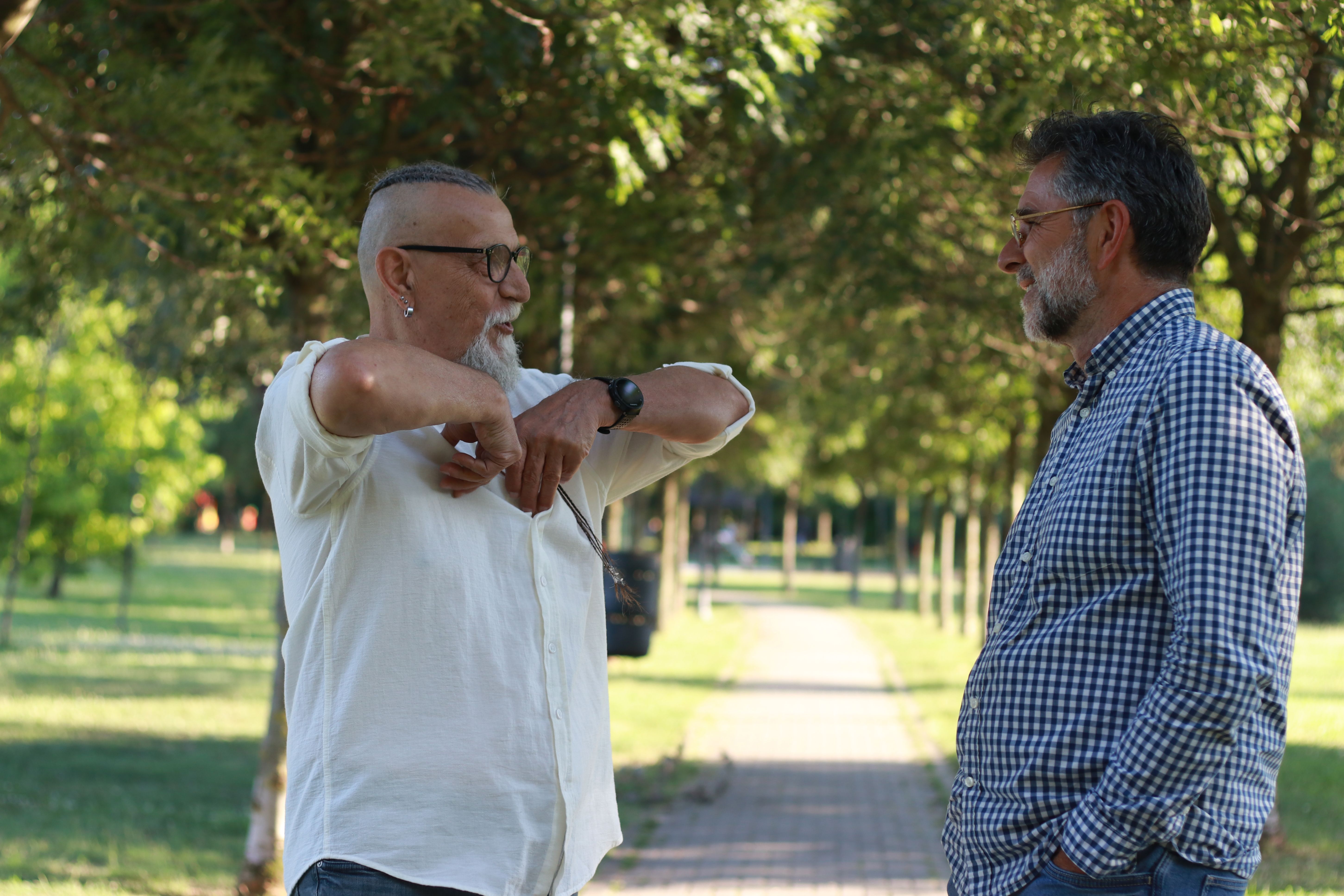 Two senior men walking trough park and talking