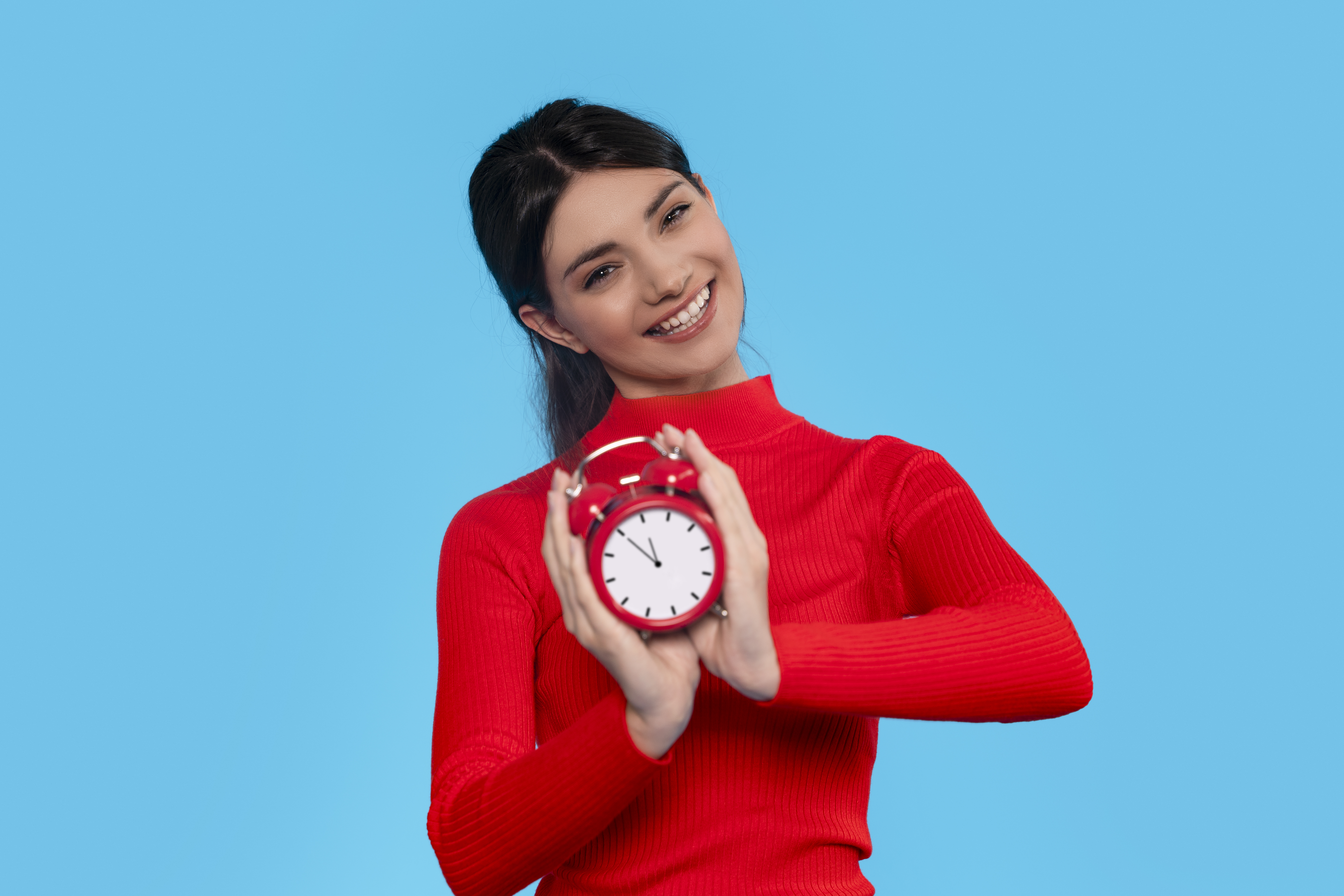 Woman Holding Red Alarm Clock Against Blue Background Woman Holding Red Alarm Clock Against Blue Background