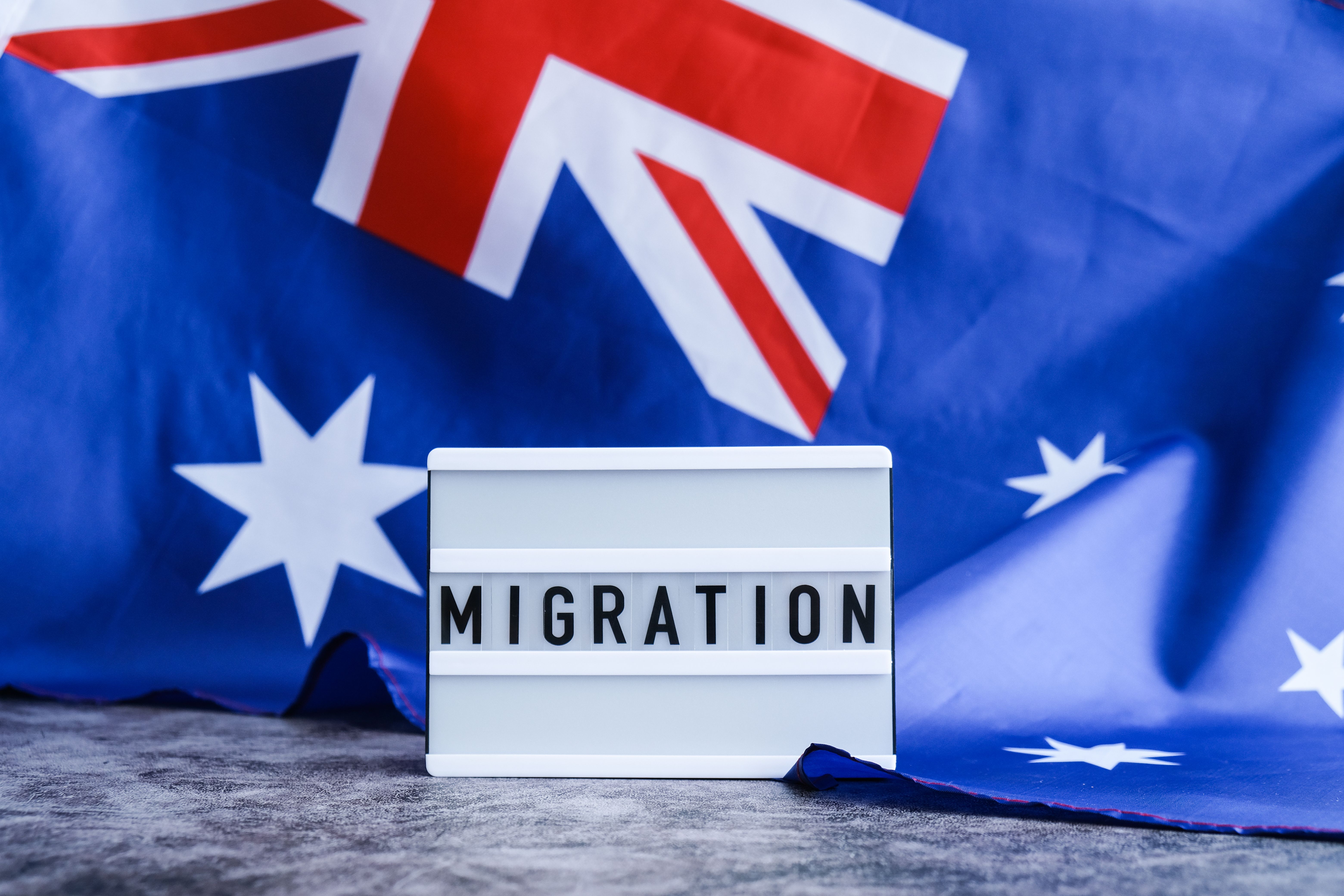 Message MIGRATION on background of Australian flag made from silk. Australia national flag with concept of tourism and traveling. welcoming