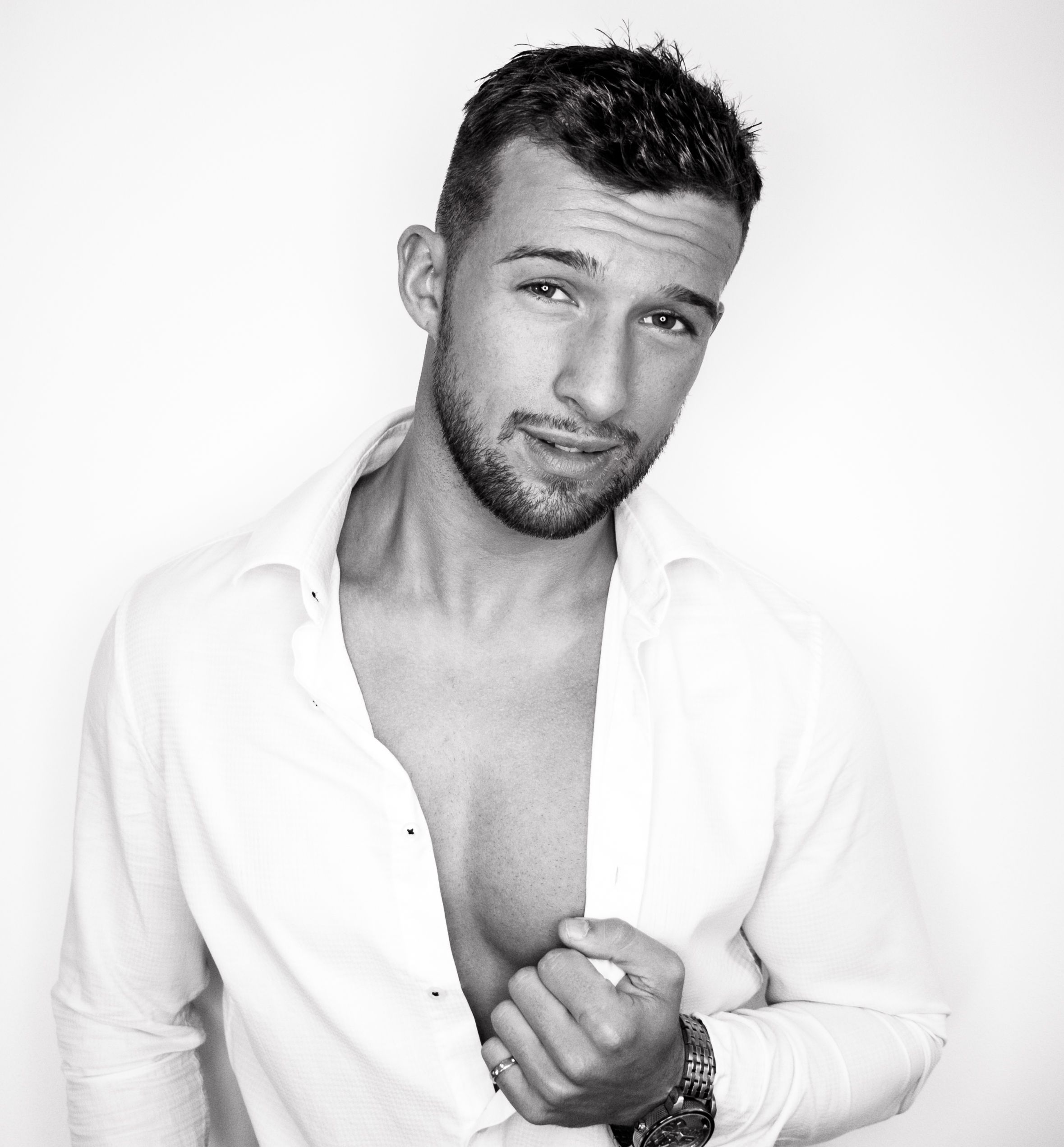 Attractive man wearing white shirt sitting isolated against wall