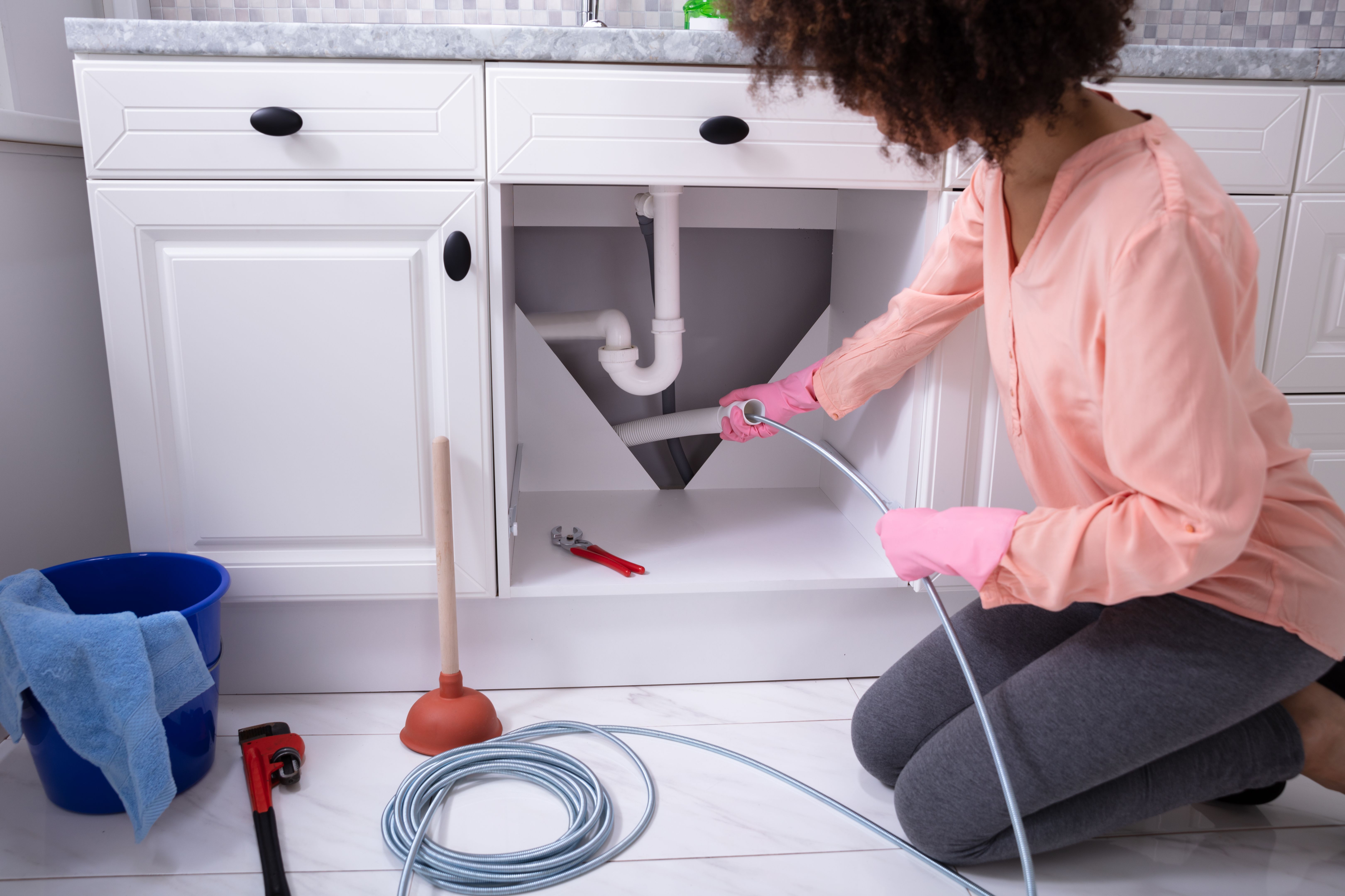 Woman Cleaning Clogged Sink Pipe