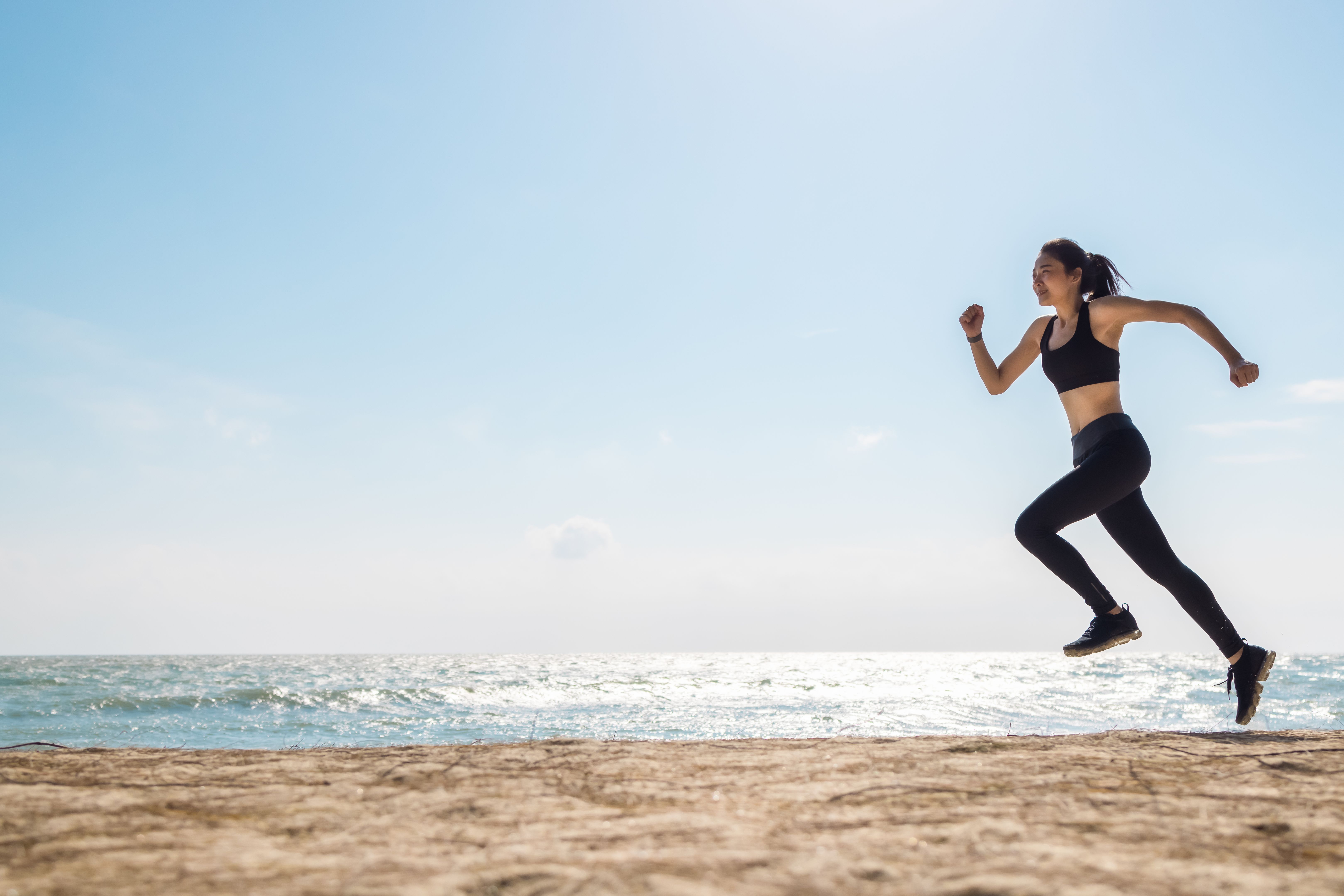 Asian healthy sport athlete girl running or jogging on beach in morning