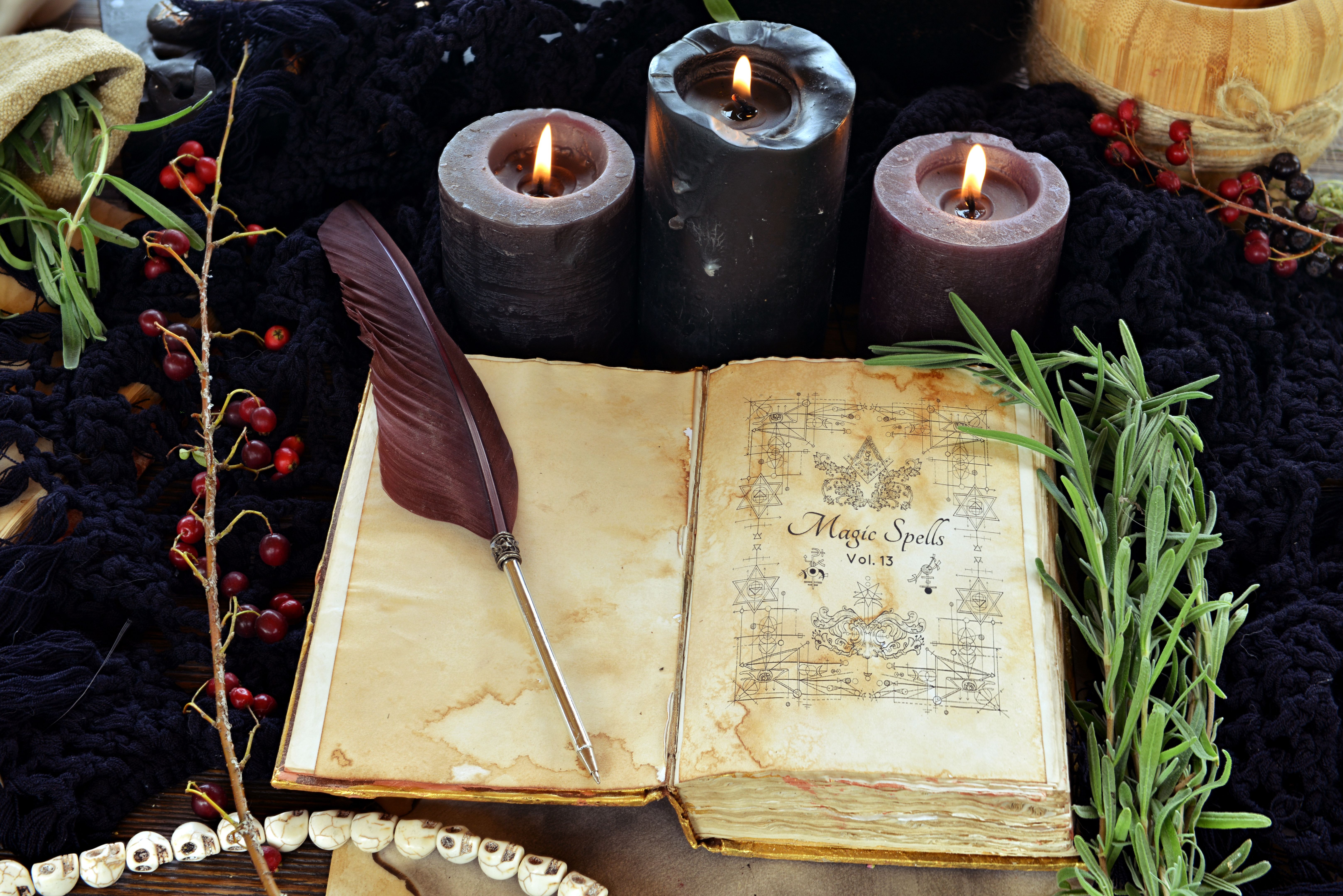 Witch book of spells with black candles on altar table. Occult, esoteric and divination still life. Mystic Halloween background with vintage objects for magic ritual