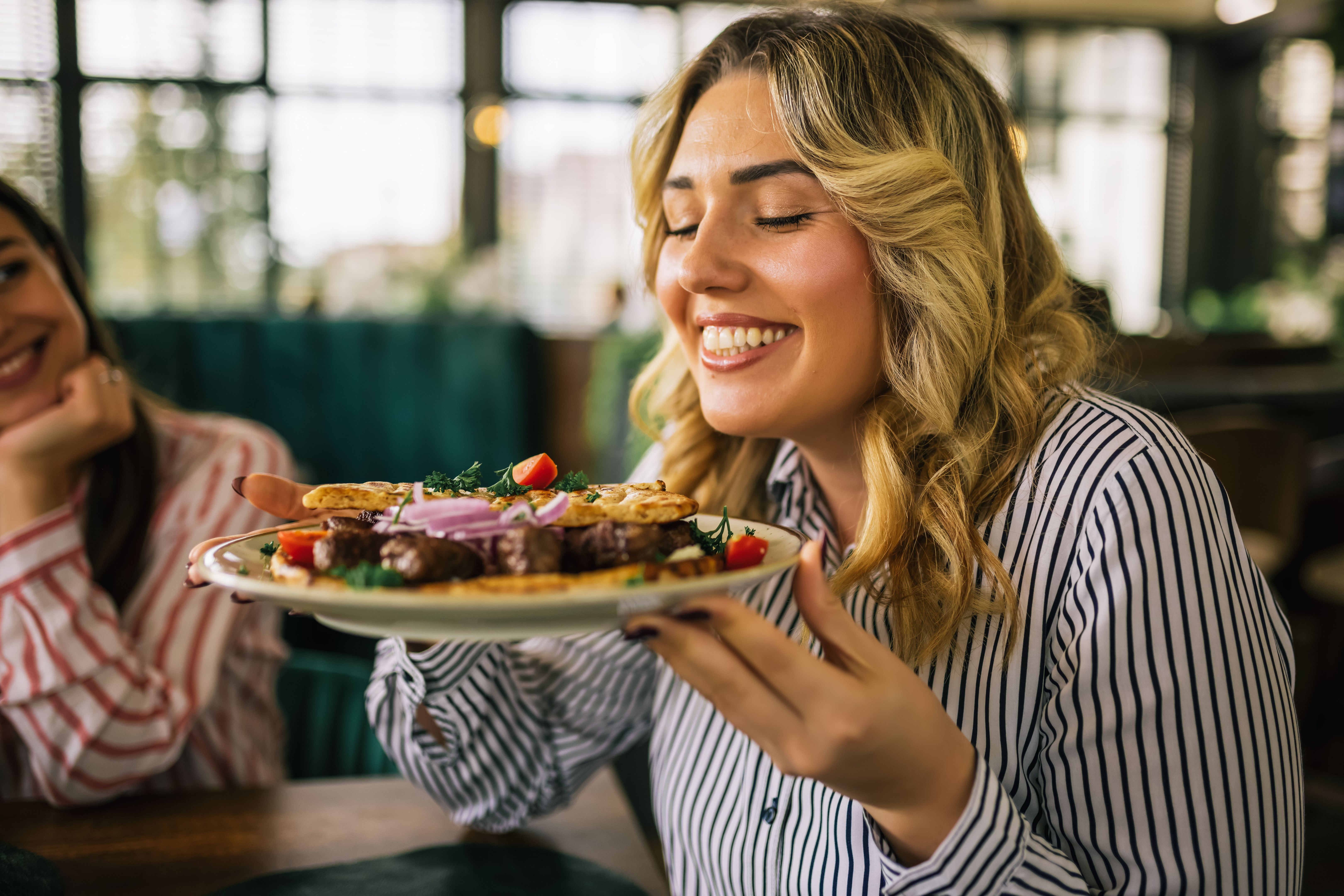 Beautiful blonde woman happy to eat grilled meat in a restaurant. Beautiful blonde woman happy to eat grilled meat in a restaurant.