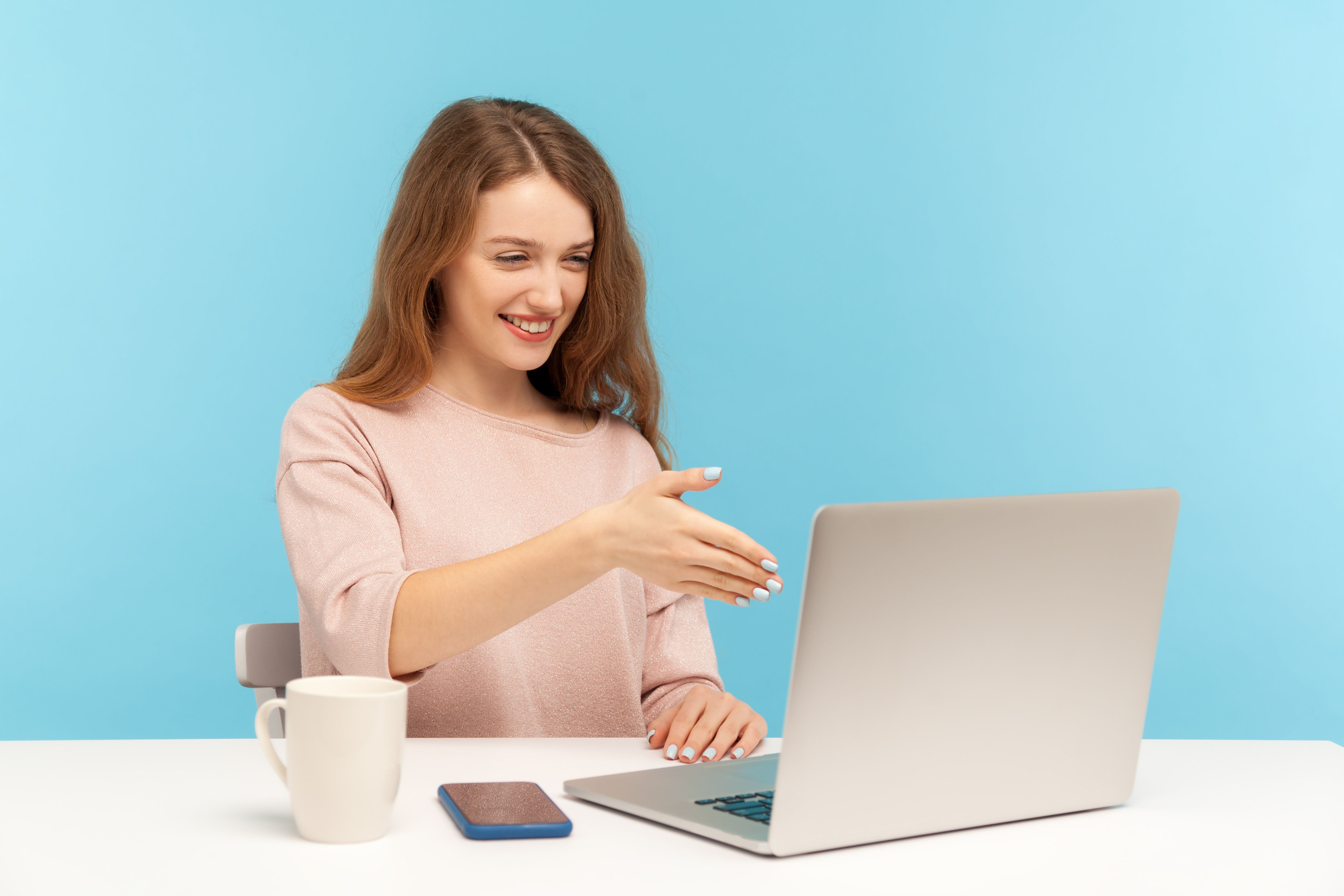 Online consulting. Happy businesswoman welcoming client with handshake and looking at laptop screen