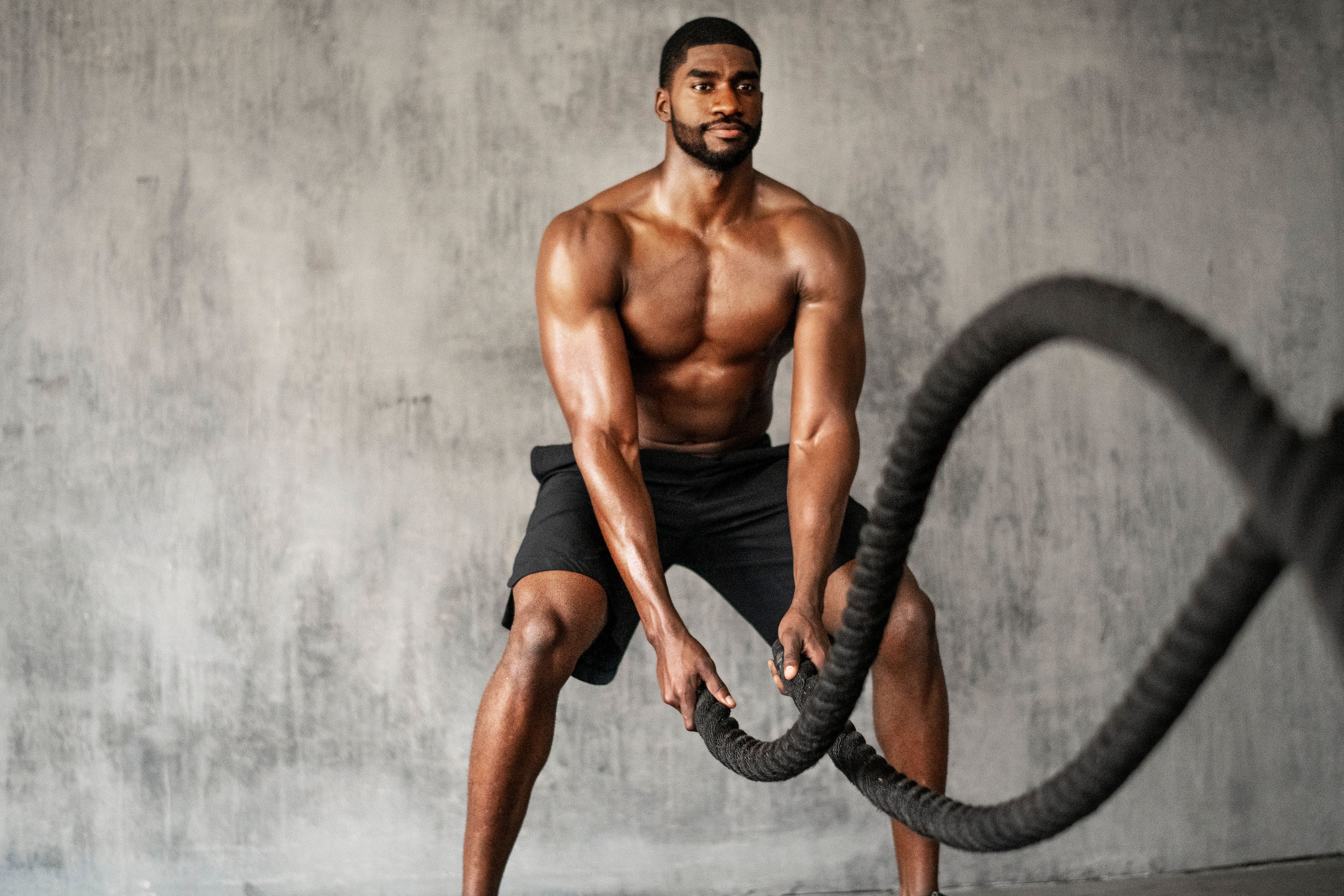 Muscular man working out on the battle ropes in a gym Muscular man working out on the battle ropes in a gym