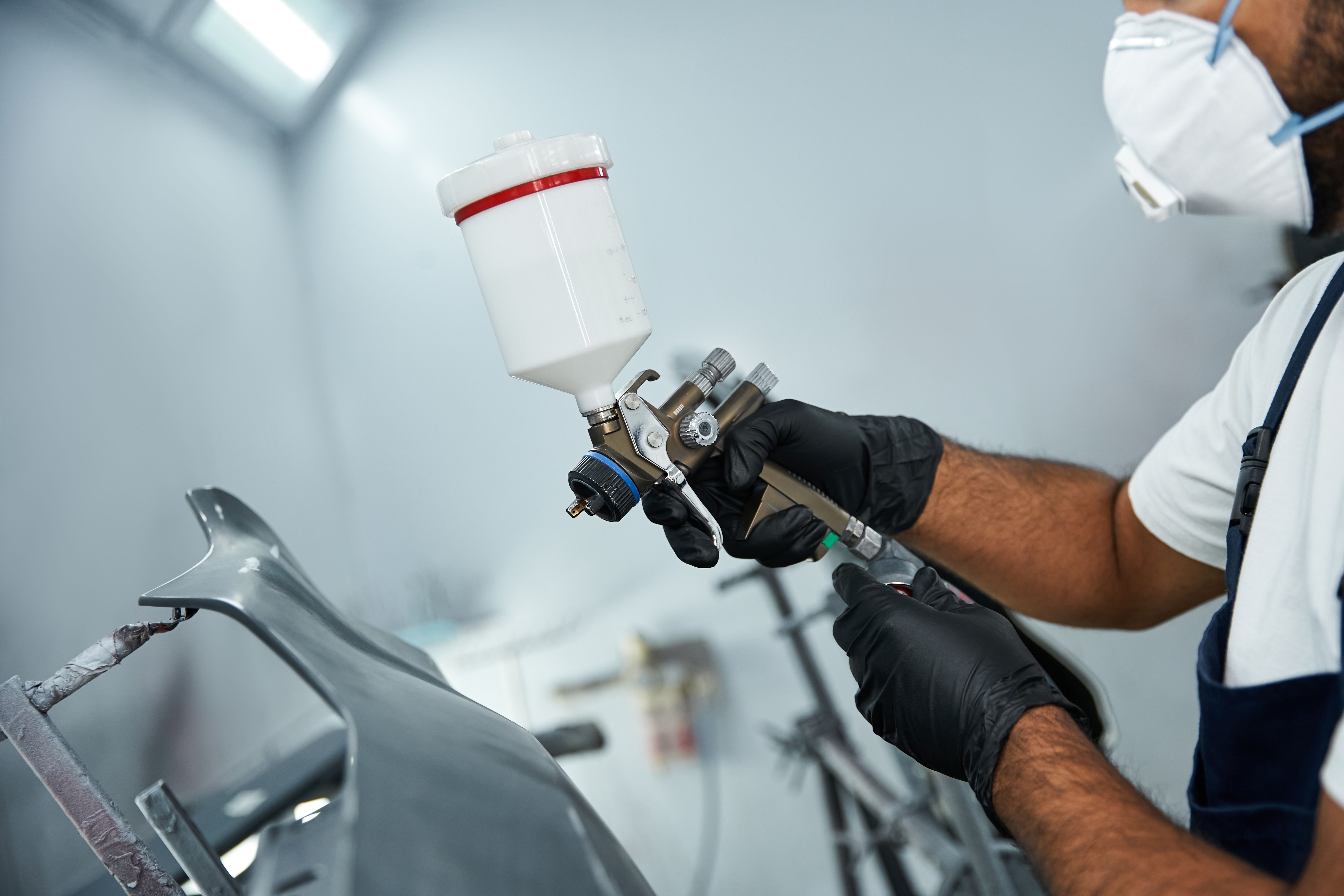 Focused mechanic applying finish in a modern auto repair service center