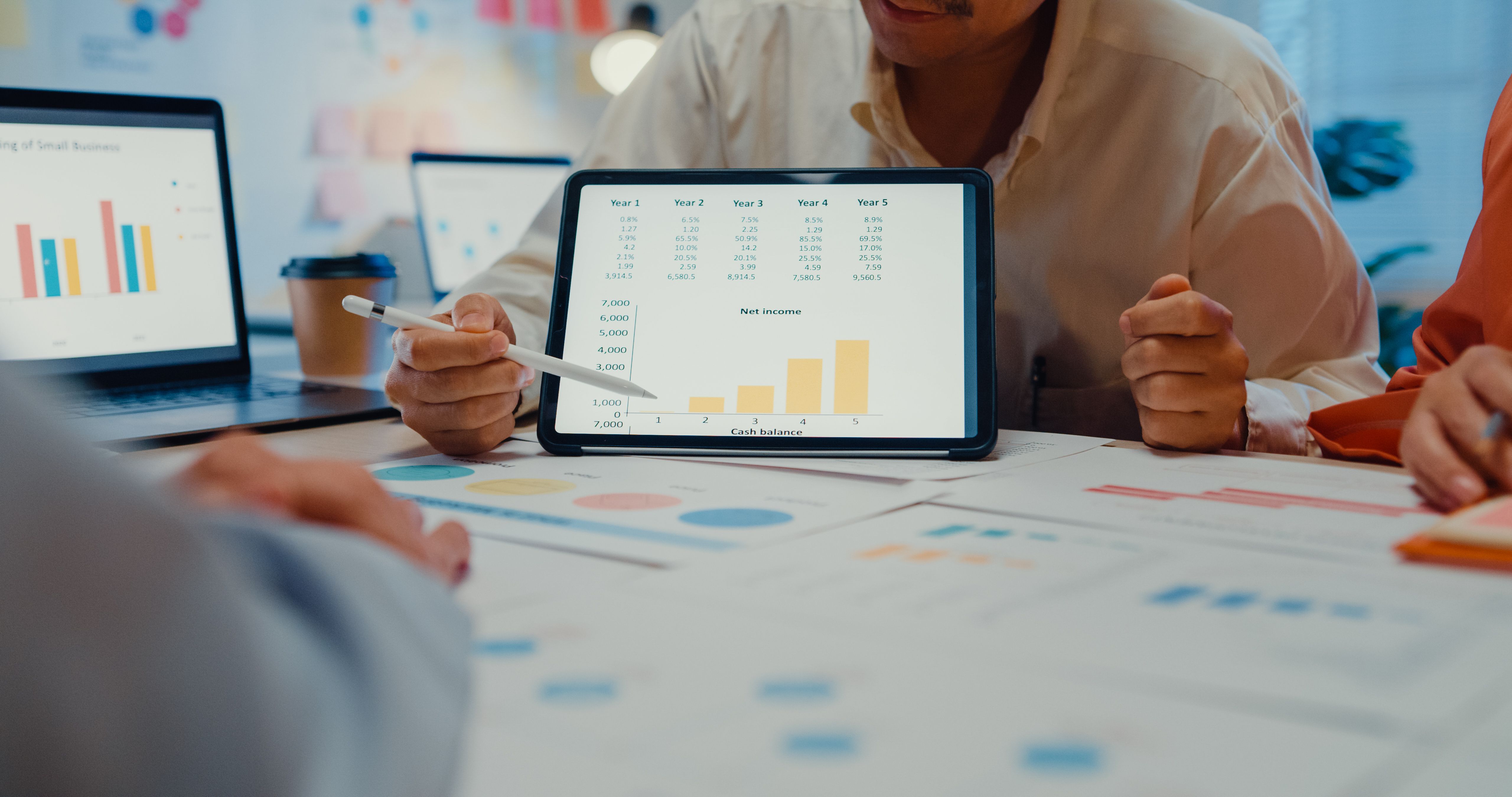 Close up of young Asian businesspeople meeting about new project with tablet in conference room at night office.