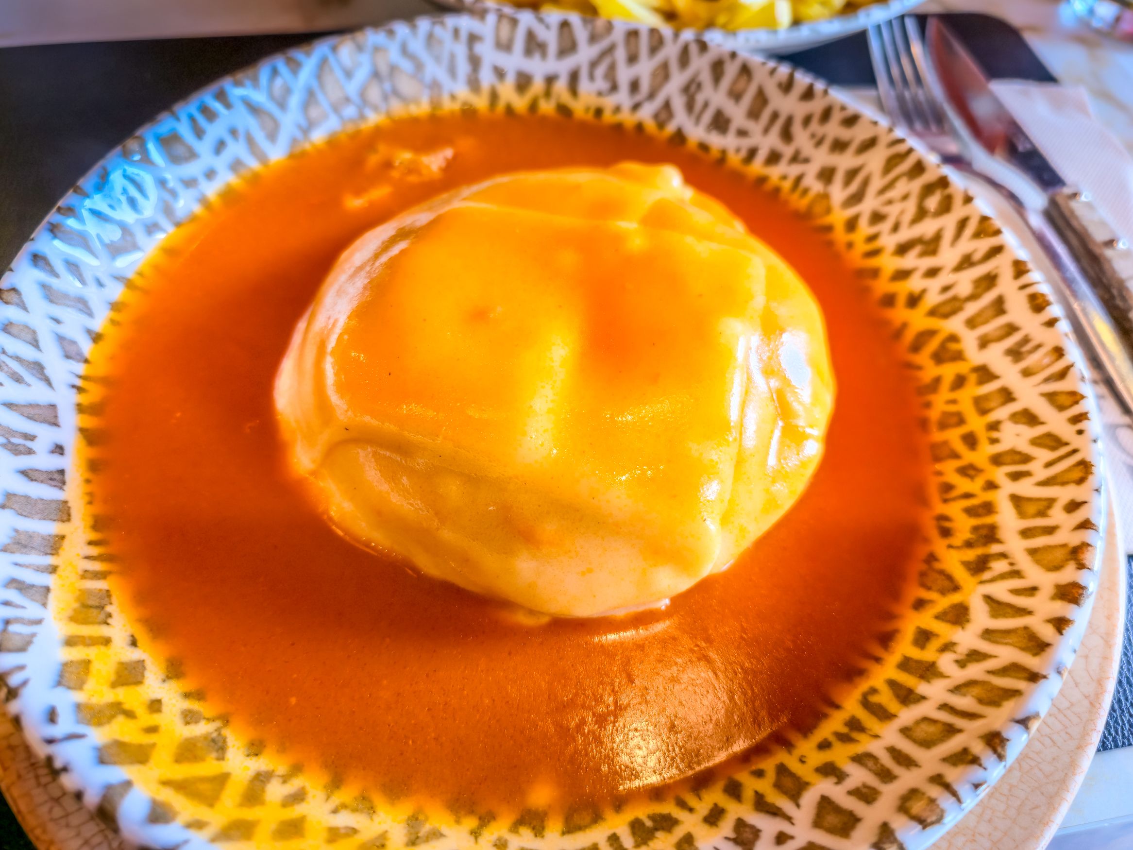 Typical sandwich from Porto know as francesinha. It's made with toasted bread and assorted hot meats over which sliced cheese is melted by the ladling of a near-boiling tomato-and-beer sauce.