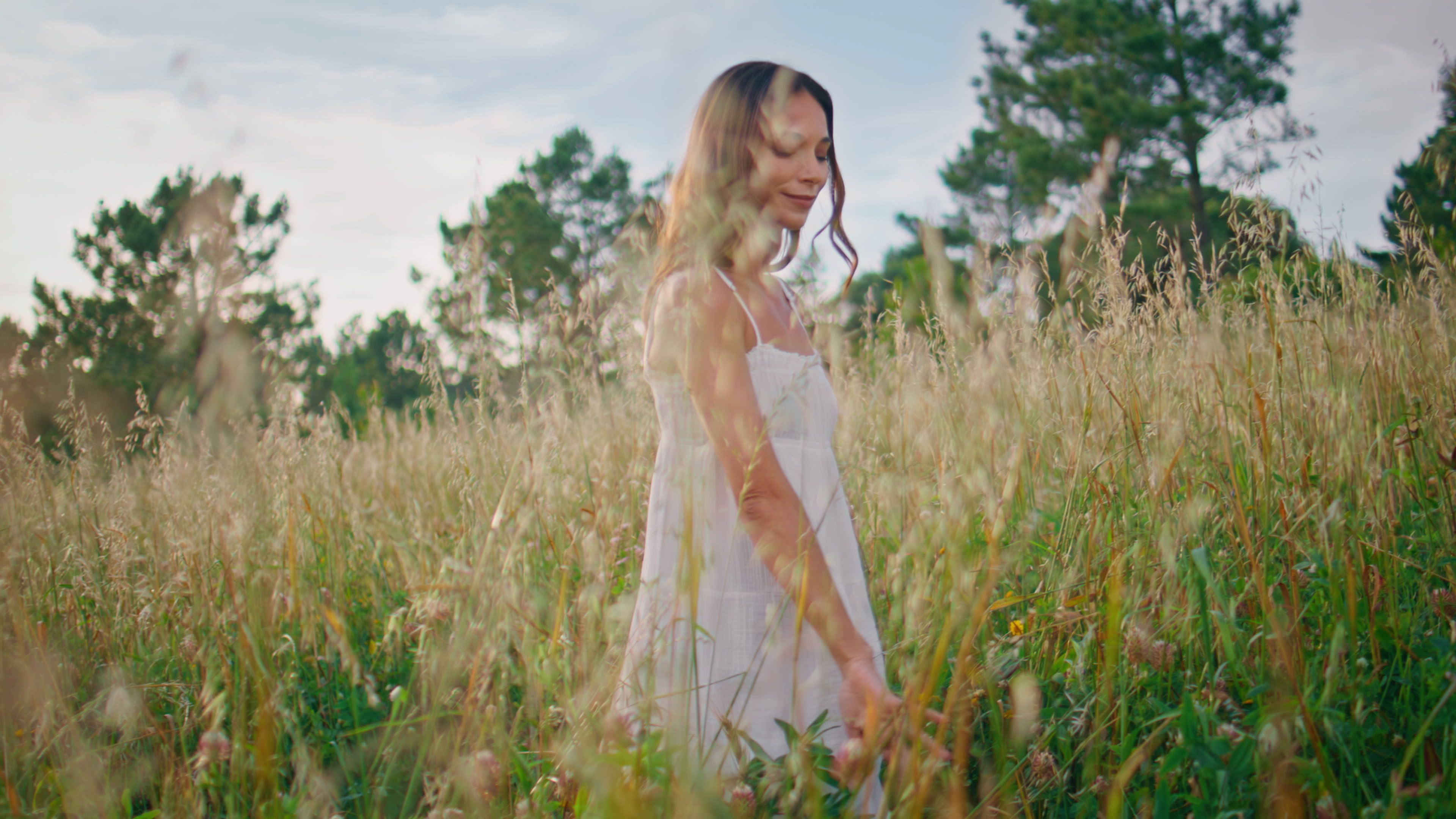 Relaxed woman strolling spikelets field in farmland closeup. Lady touching wheat