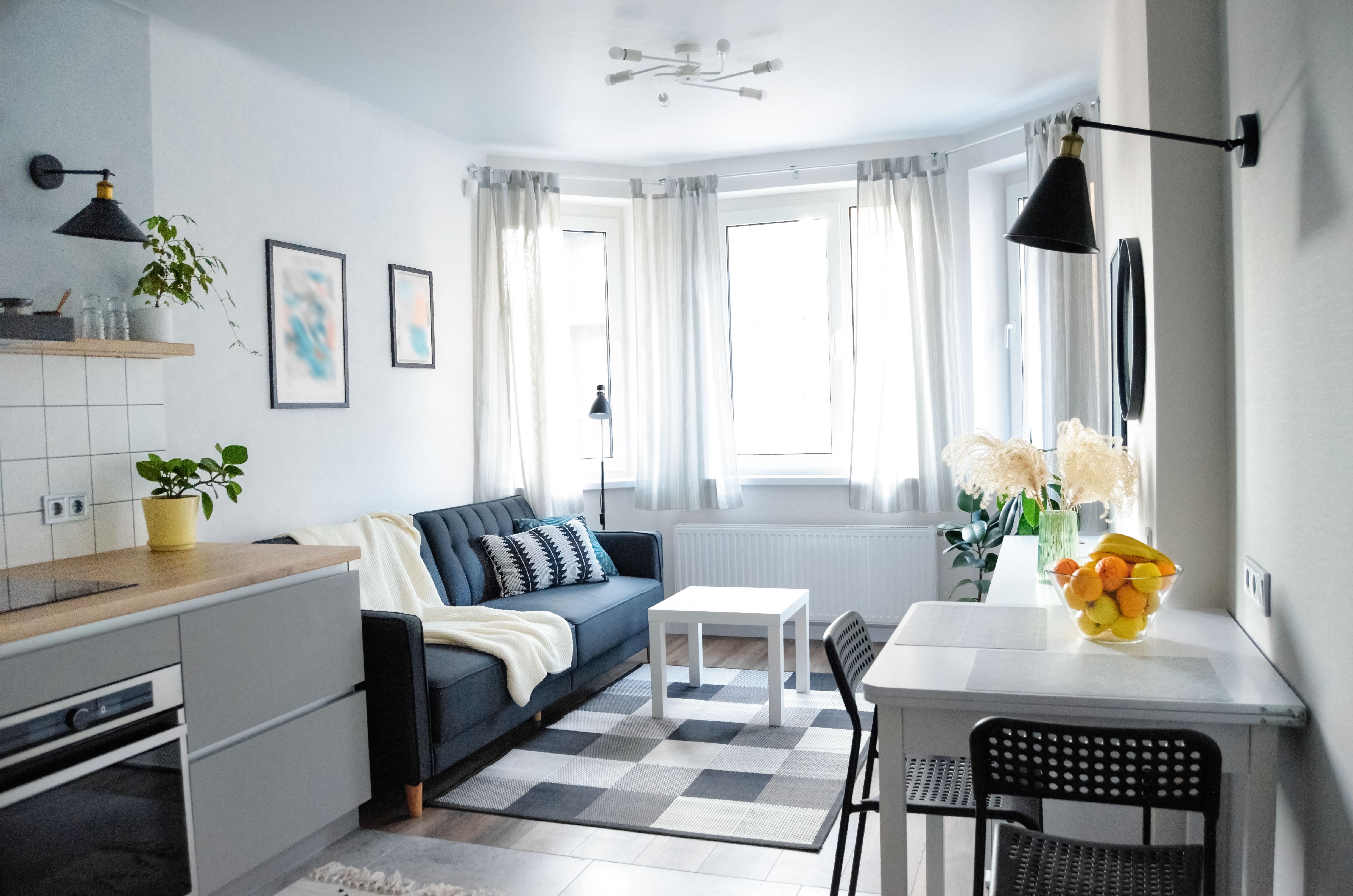 Scandinavian interior style modern studio small apartment in white and grey colors, furniture in living area and kitchen area Scandinavian interior style modern studio small apartment in white and grey colors, furniture in living area and kitchen area