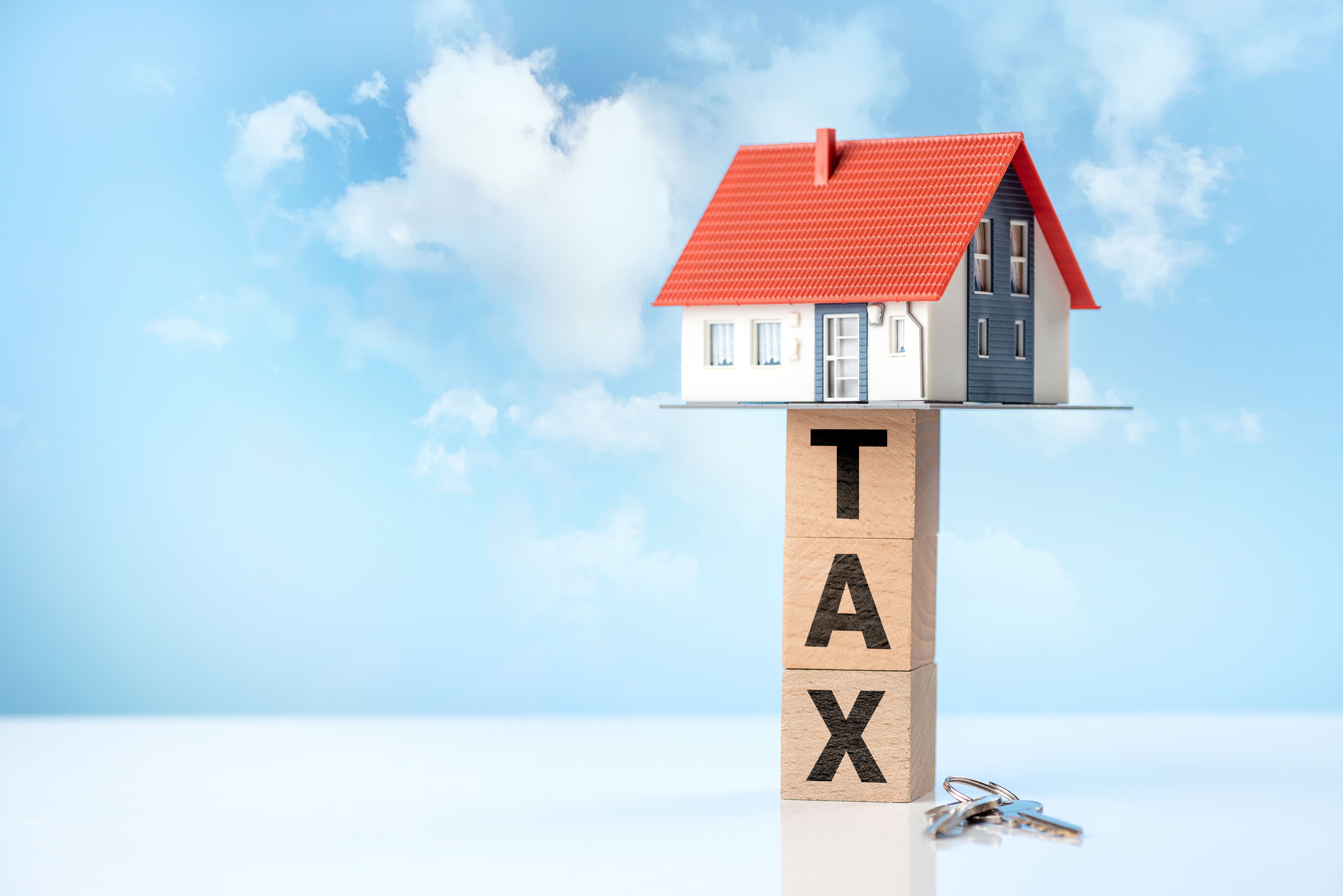 A dreamlike house among the clouds and TAX word on wooden cubes. Property tax concept.
