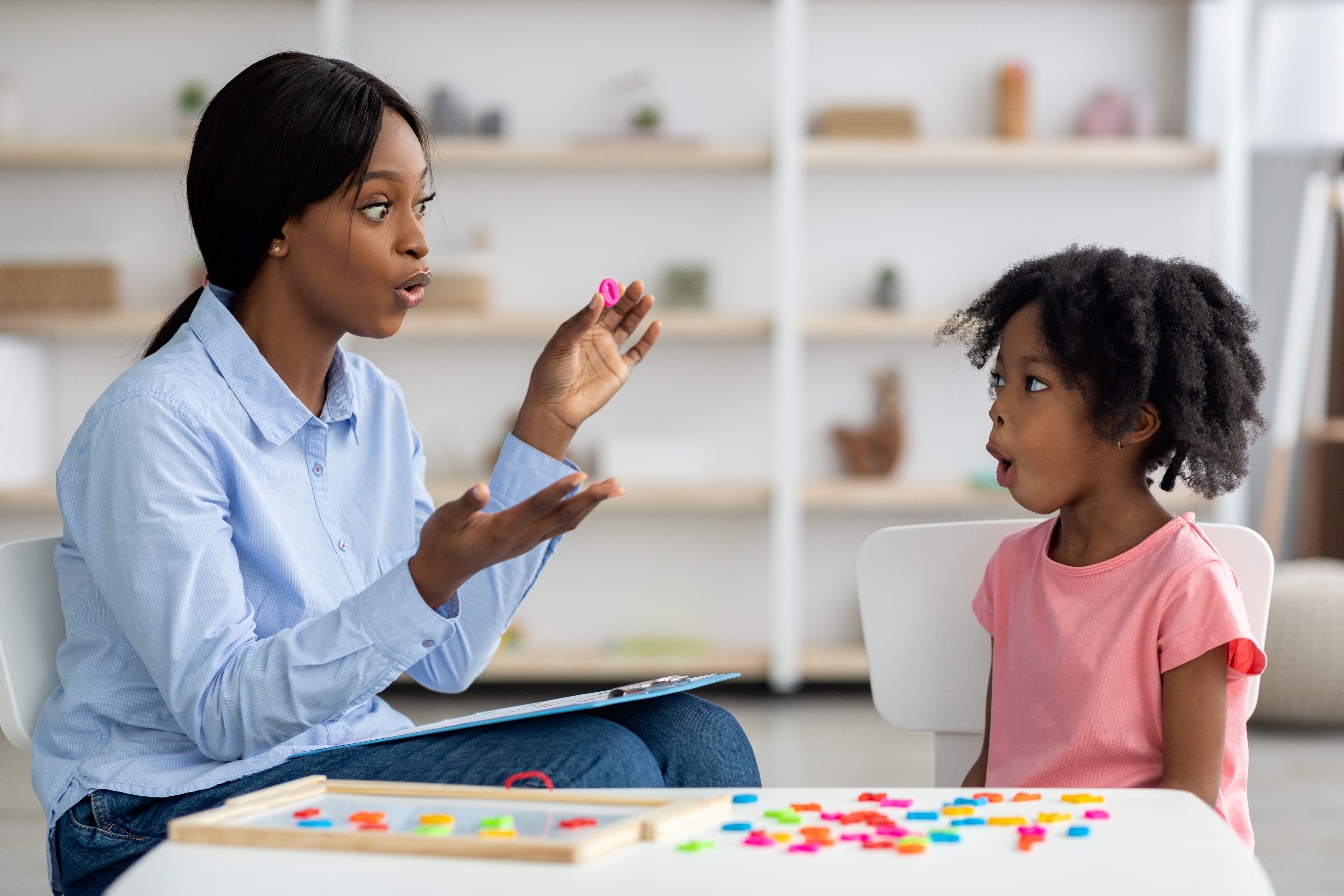 Speech therapist working with little black girl