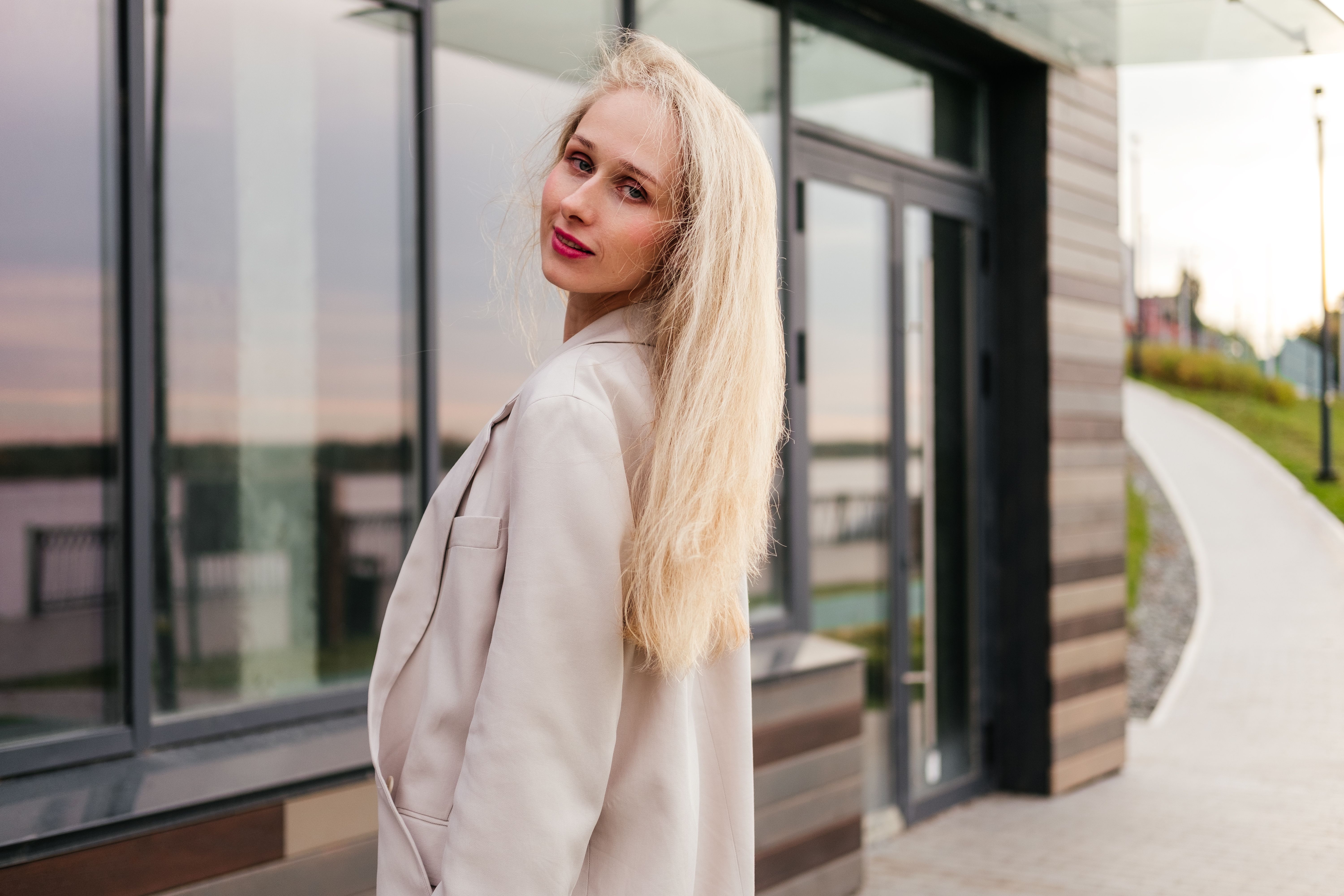 Smiling woman in white in white clothes standing on street near building outdoor. Businesswoman looking at camera Smiling woman in white in white clothes standing on street near building outdoor. Businesswoman looking at camera