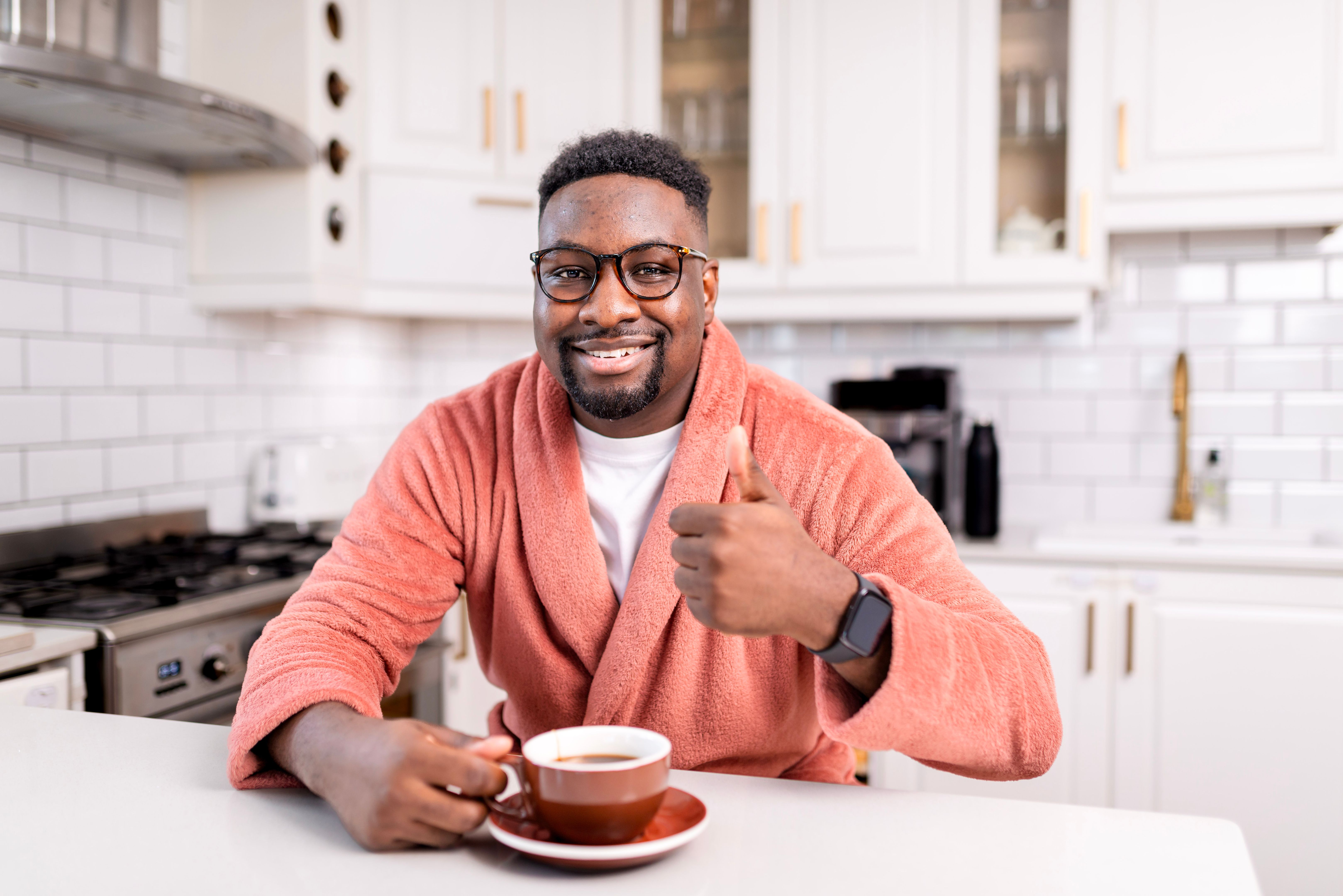 Smiling Man in Kitchen Enjoying a Cup of Coffee Giving a Thumbs-Up Gesture Smiling Man in Kitchen Enjoying a Cup of Coffee Giving a Thumbs-Up Gesture