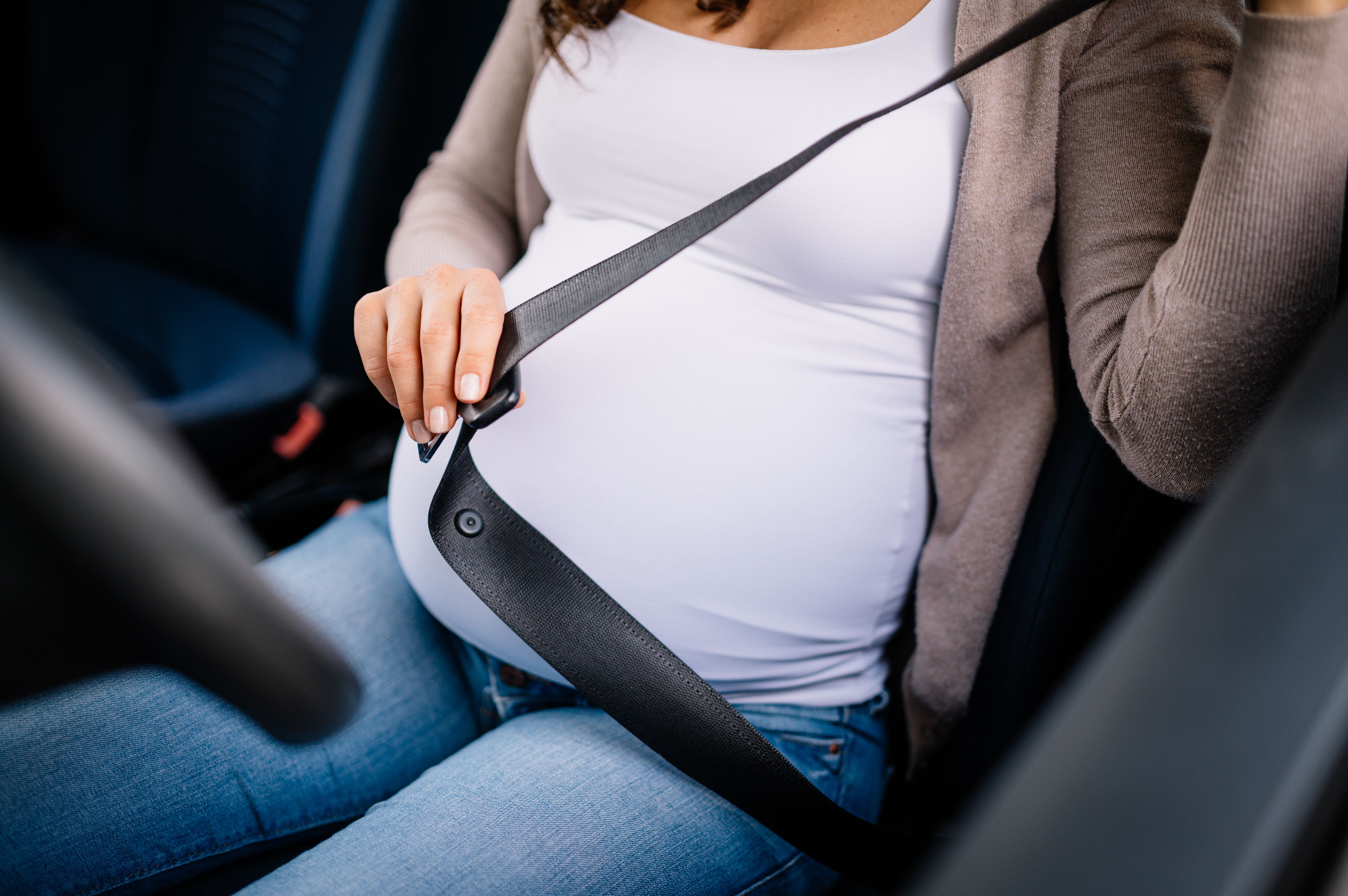 Closeup of pregnant woman sitting in car and fasten seat belt Closeup of pregnant woman sitting in car and fasten seat belt